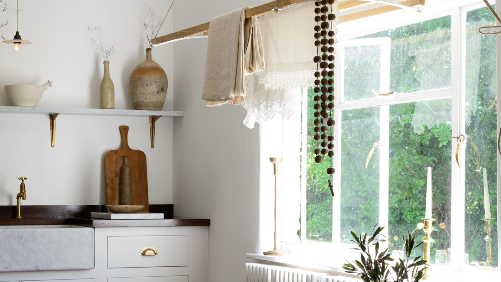 White laundry and utility room with a wooden ceiling rack. There is open shelving with stone vases and wooden cutting board in view
