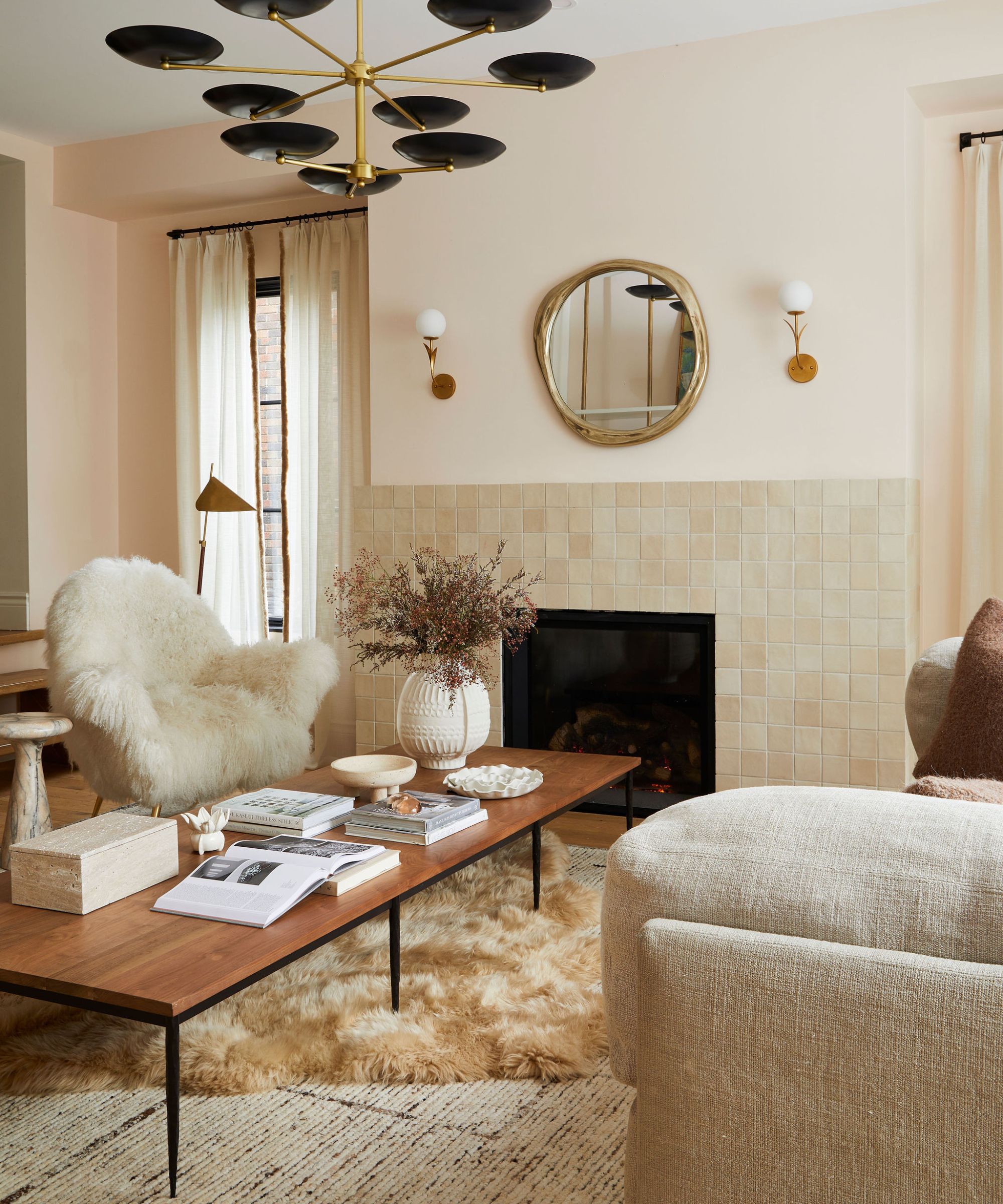 Ein neutrales Wohnzimmer mit großen schwarzen Metallfenstern, die eine Wand einnehmen. Es gibt ein großes beiges Sofa, auf dem ein Hund sitzt, und auf der linken Seite einen Baum. Vorne steht ein großer Couchtisch aus Holz