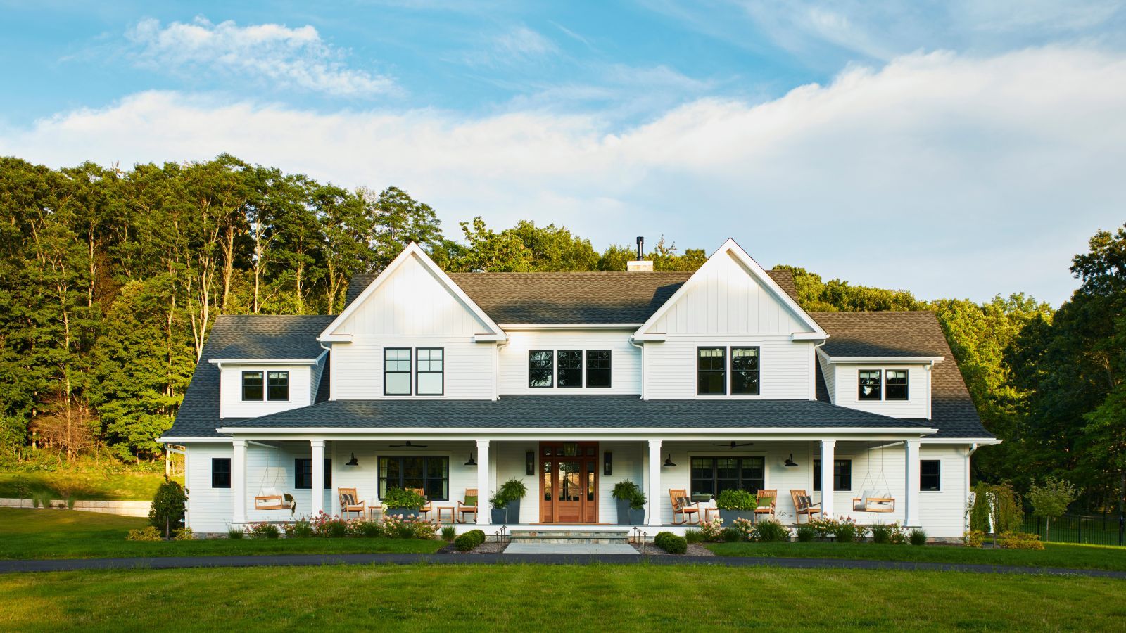 large white Connecticut home with a large porch, porch furniture and front lawn