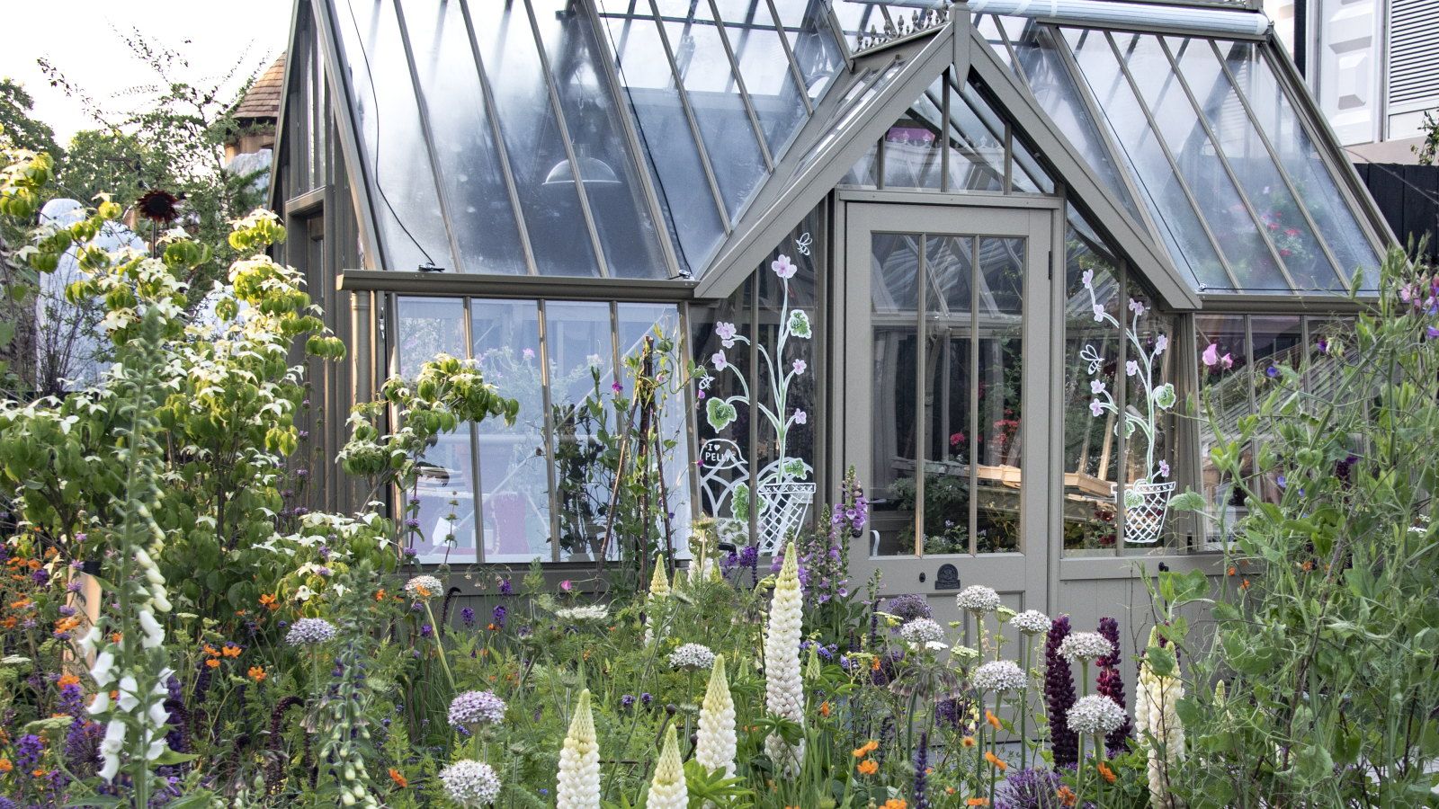 A grand greenhouse surrounded by flower-filled beds at the Chelsea Flower Show