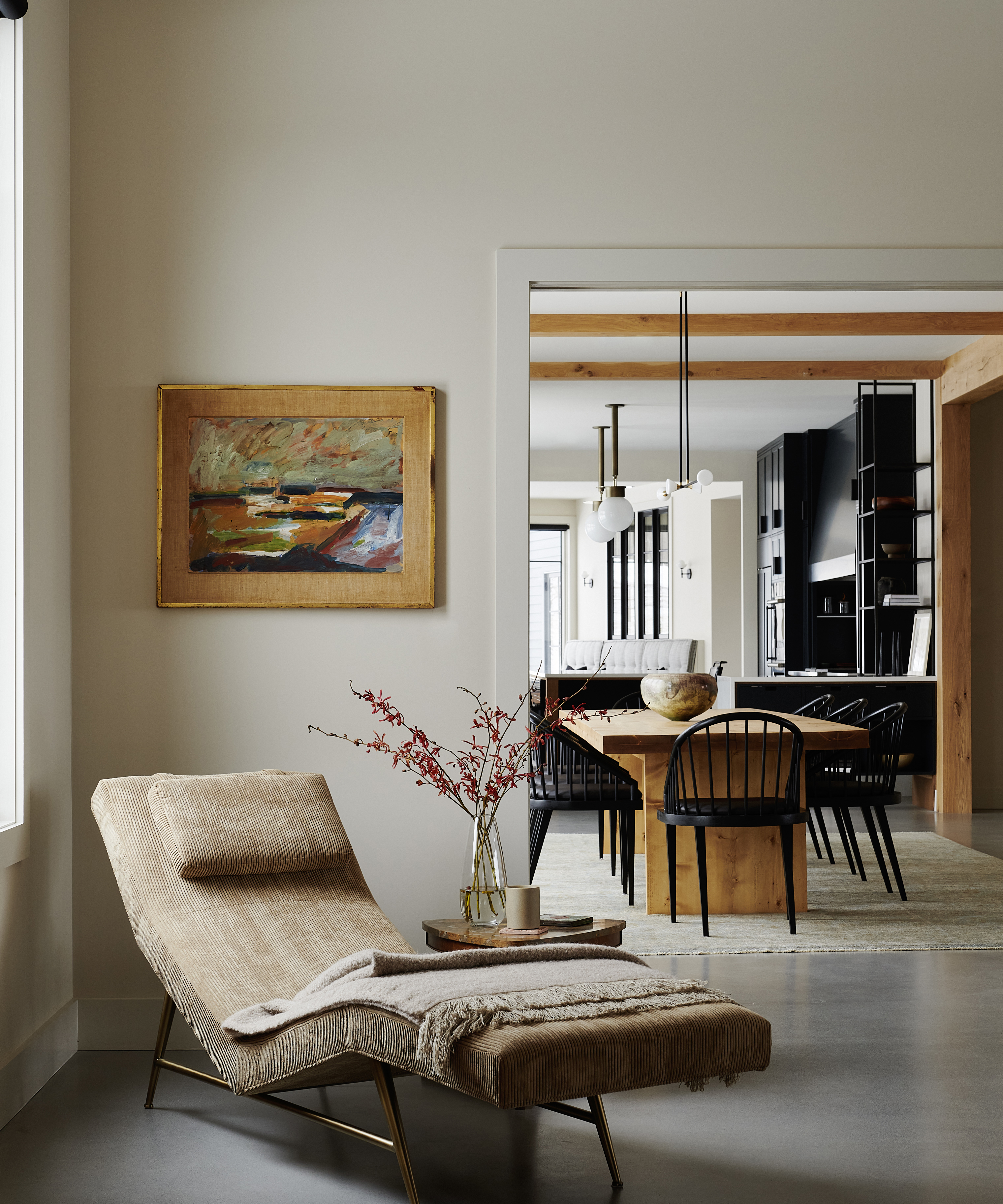 eine Chaiselongue in der Ecke eines weißen Wohnzimmers neben einer Tür mit Blick auf einen Essbereich