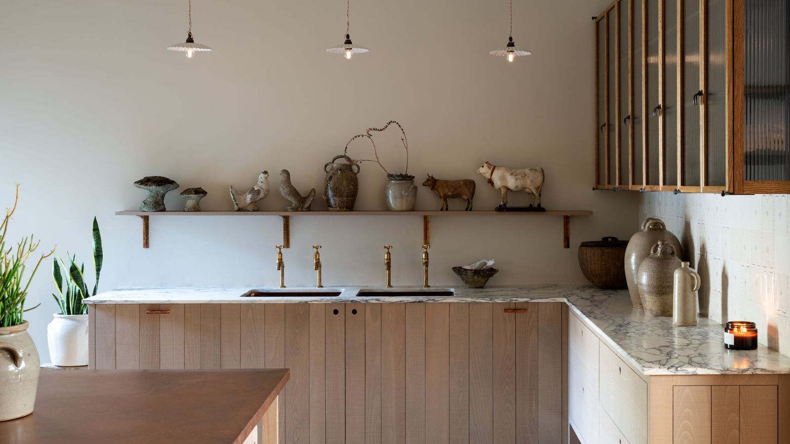 Paneled kitchen cabinets in natural wood with marble counters