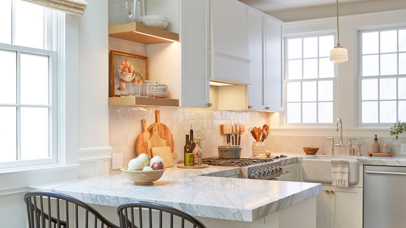 Eine kleine weiße Halbinselküche mit Marmorarbeitsplatten und Holzdekor