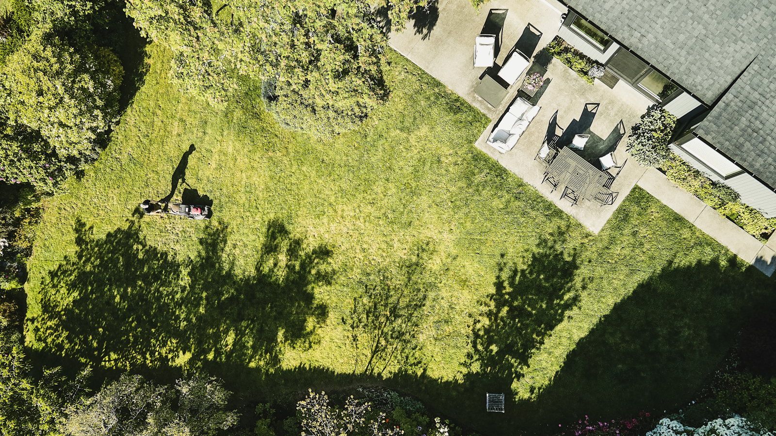 An aerial view of a man mowing the grass in his backyard