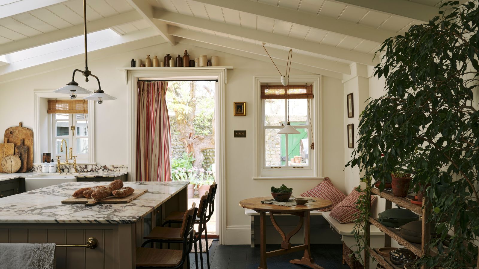 Ein neuer Küchenanbau mit gewölbten, getäfelten Decken, olivgrünen Schränken, Marmorarbeitsplatten und einem gemütlichen Essbereich