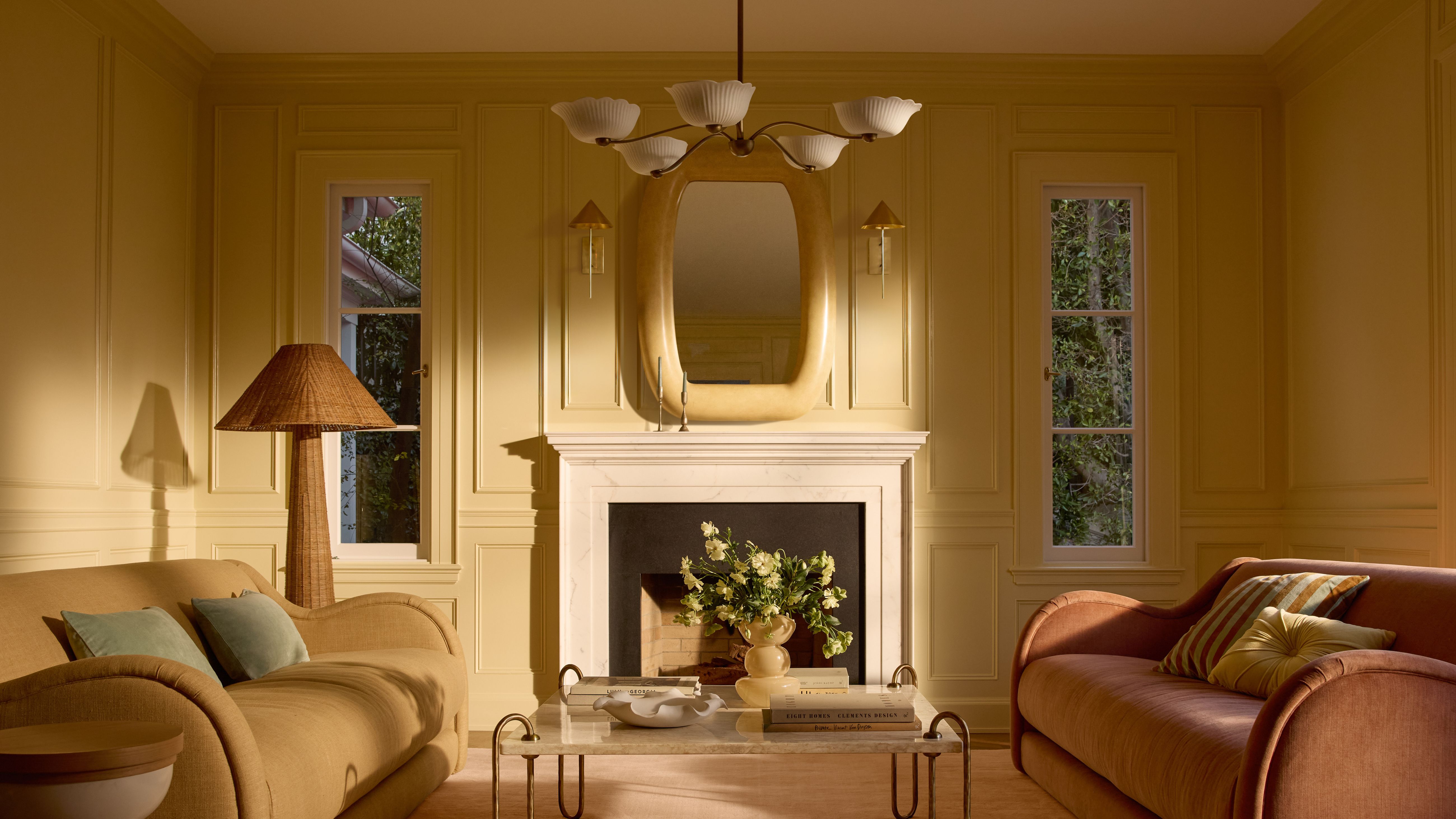 Buttergelbes, liebevolles Zimmer mit skulpturalen Möbeln in gedämpften Pastelltönen und einem von Blumen inspirierten Kronleuchter an der Decke