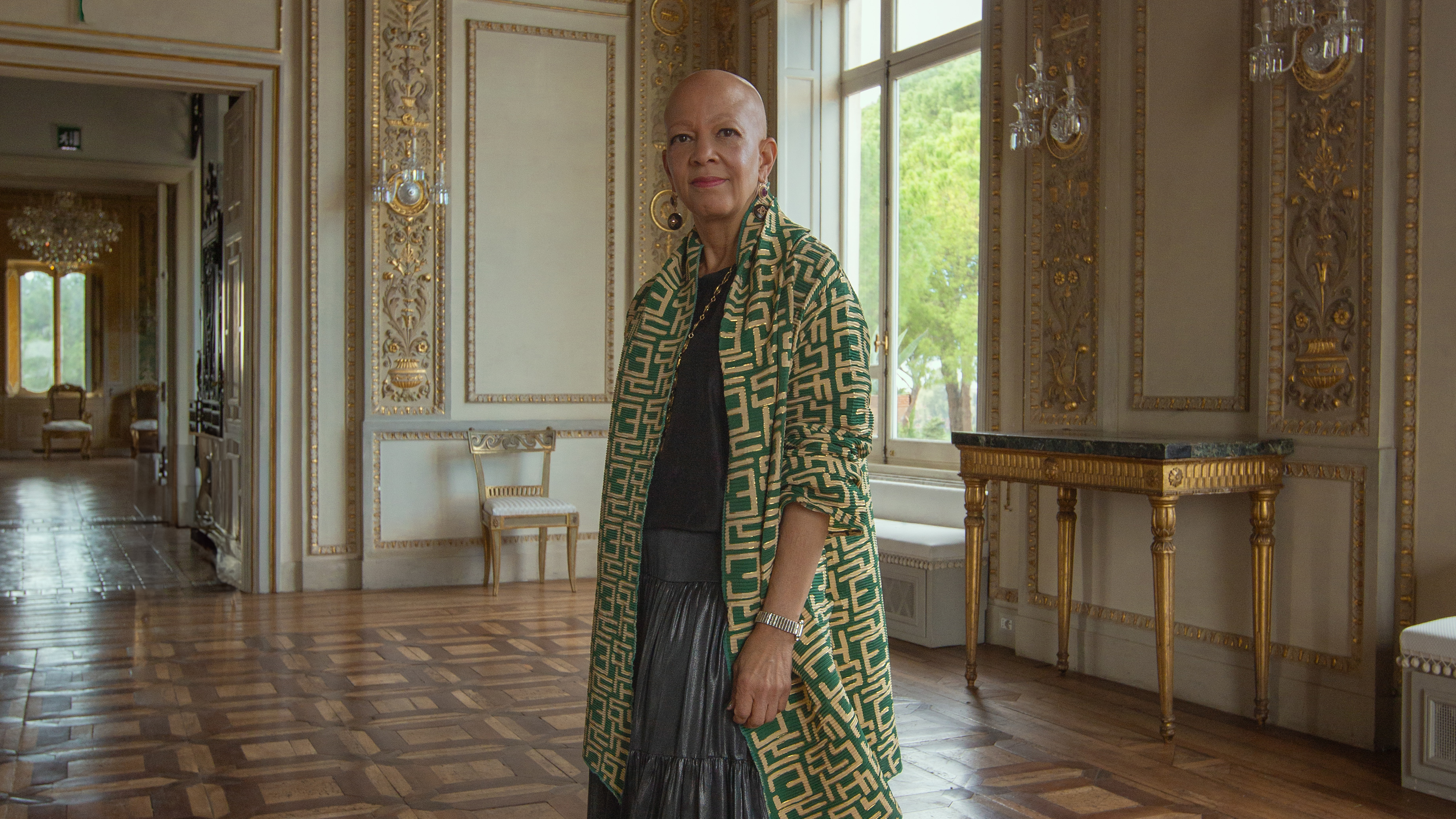 Shelia Bridges blickt in einem grünen Mantel in einem großen Palazzo in die Kamera
