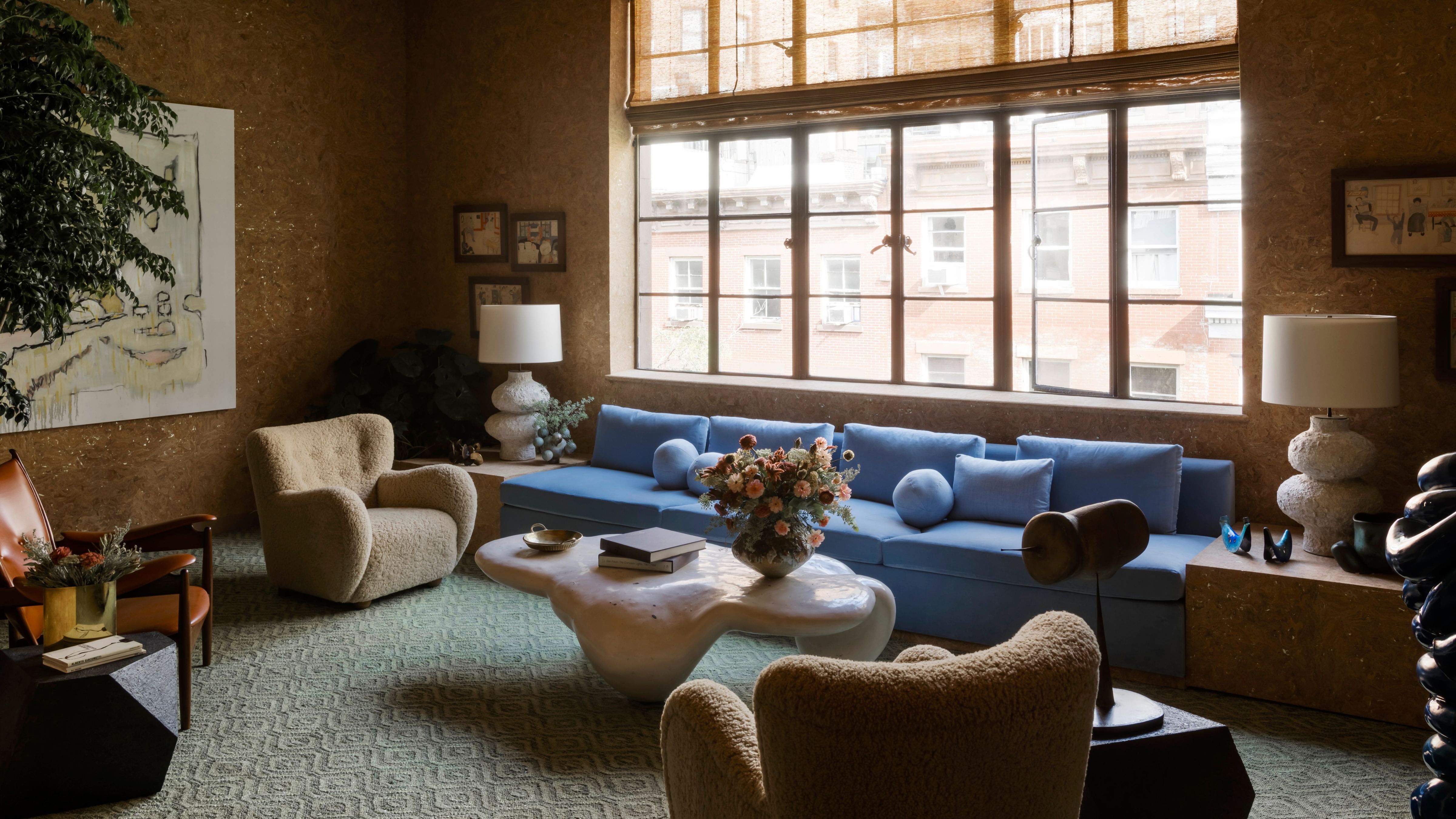 NYC-Wohnzimmer mit Korkwänden, geschwungenen Akzentstühlen und einem niedrigen, immergrünen Sofa