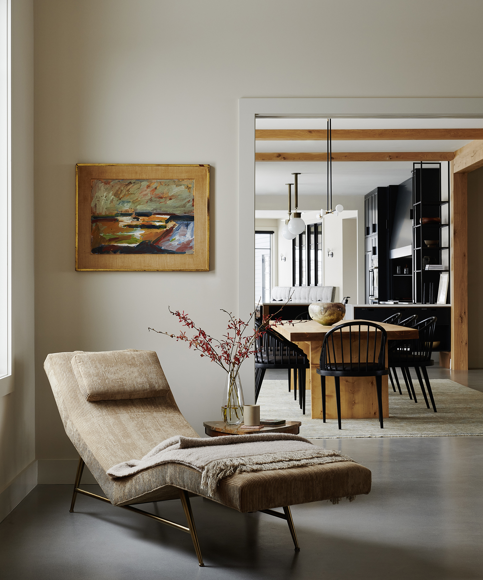 Chaiselongue in einer Ecke eines Wohnzimmers mit Blick durch eine Tür auf die Wohnküche dahinter