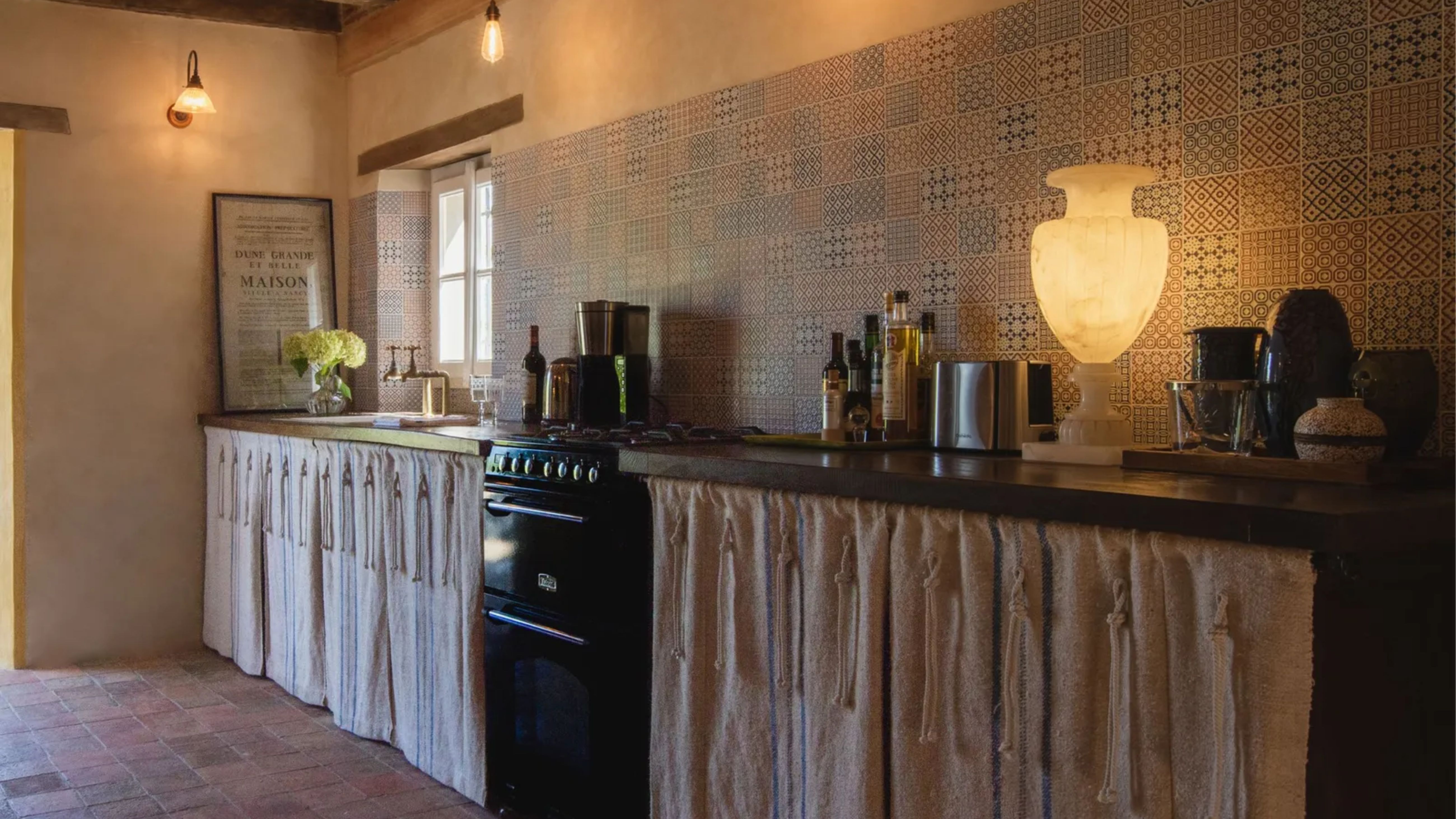 Eine französische Landhausküche mit Schrankvorhängen und mehrschichtiger Beleuchtung