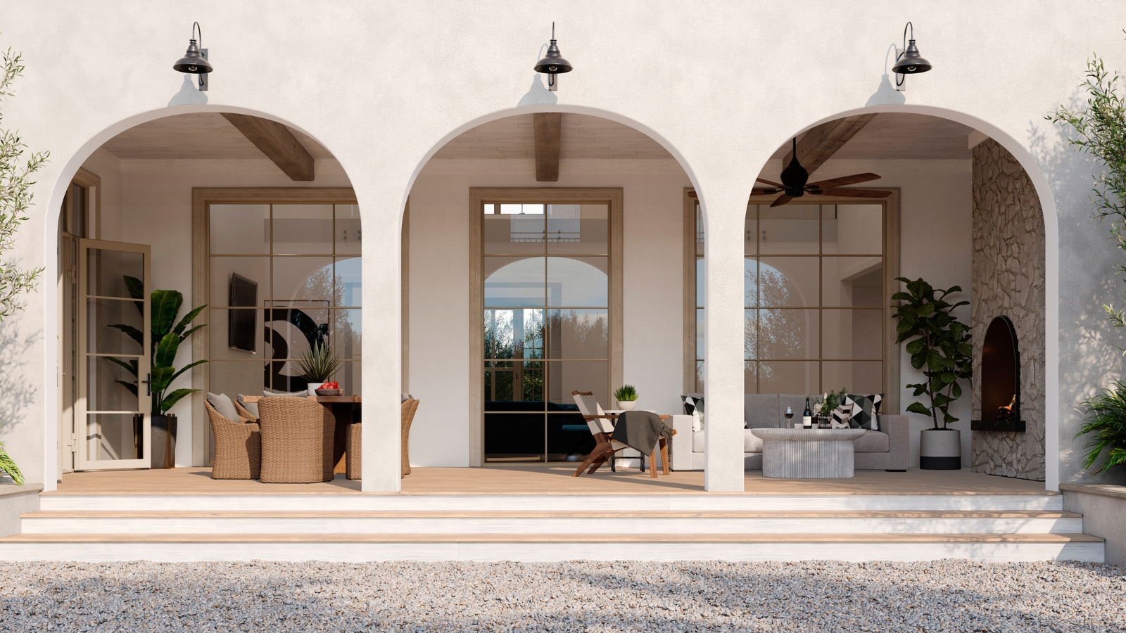 Helle Außenfassade des Hauses mit drei großen Torbögen, freiliegenden Fenstern und einer Außenveranda mit Rattanmöbeln und hohen Pflanzen.