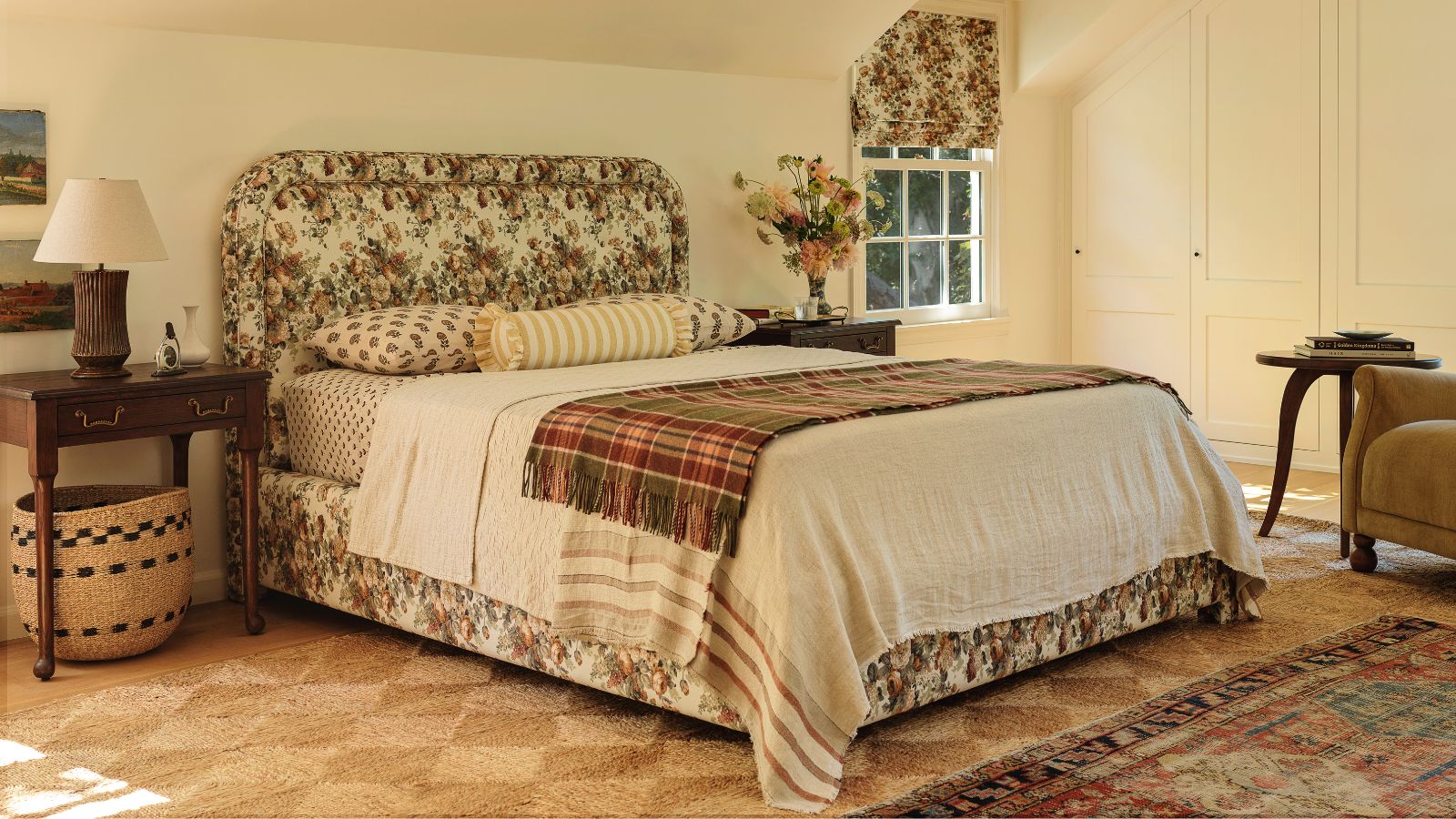 Schlafzimmer im Vintage-Stil, entworfen von Heidi Caillier für ihre Zusammenarbeit mit Lulu und Georgia, mit einem natürlich gewebten Teppich, einem gepolsterten Bett mit Blumenmuster und einem Samtsessel