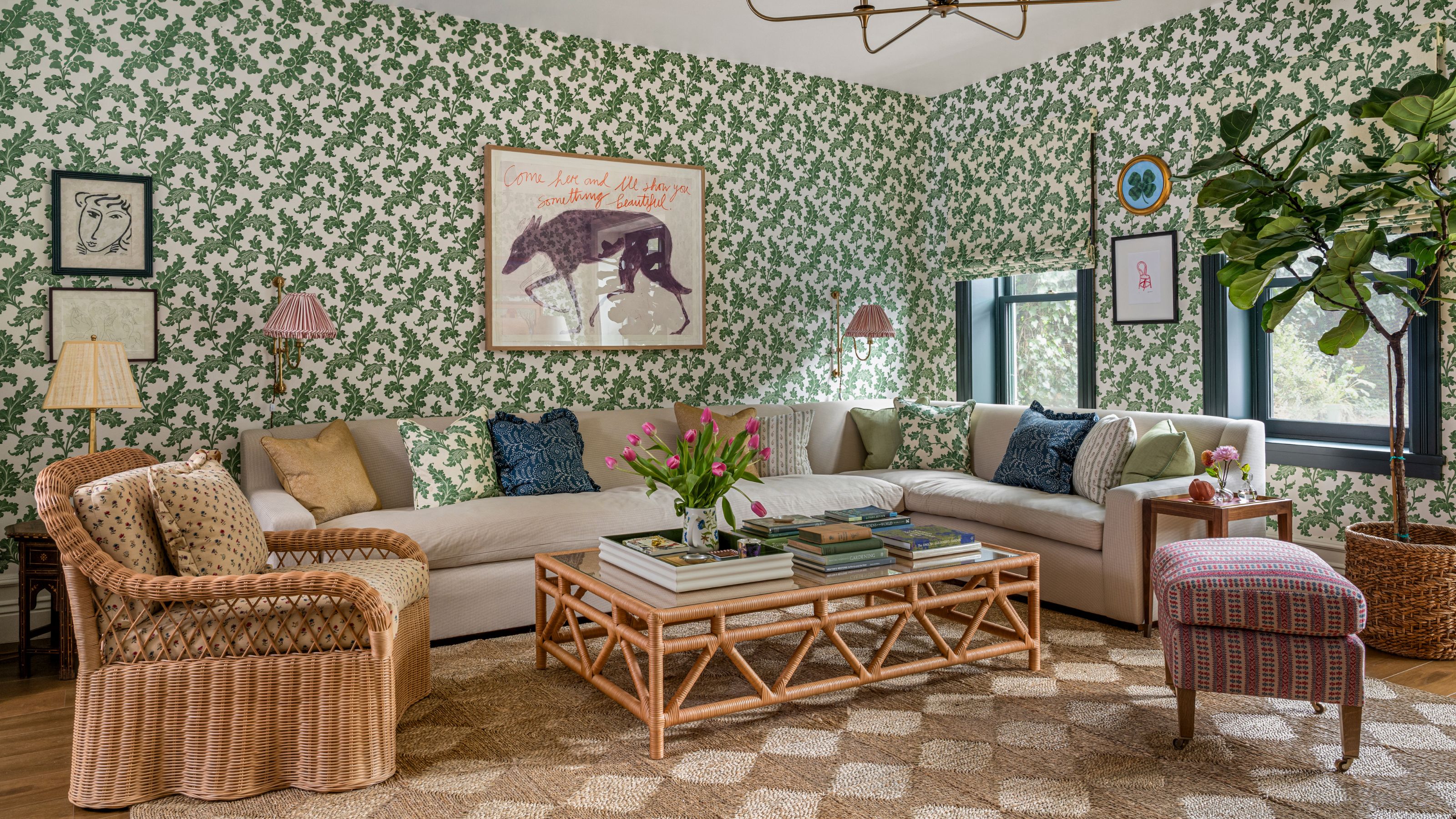Ein Familienzimmer mit grünen Blumentapeten, einem großen Sofasofa, einem rautengewebten Rattanteppich, Korbmöbeln und vielseitigen Kunstwerken