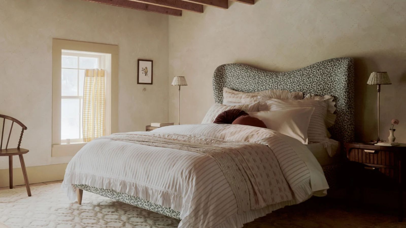 Muted spring bedroom, large bed with patterned headboard, pink bedding, two tall table lamps on wicker bedside tables