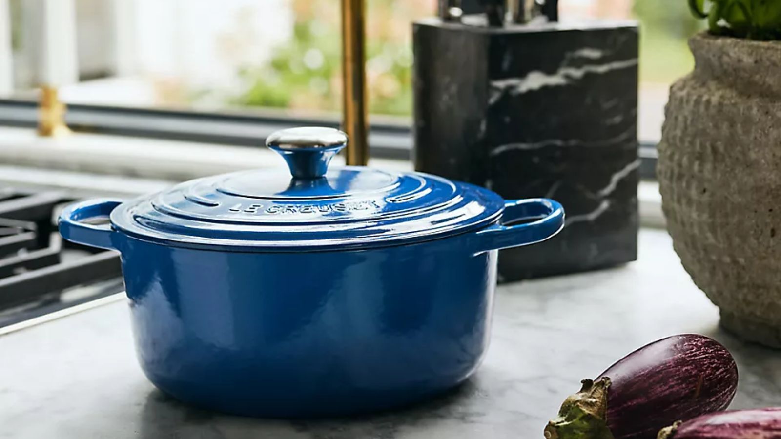 Ein dunkelblauer Schmortopf von Le Creuset auf einer Küchentheke aus Marmor