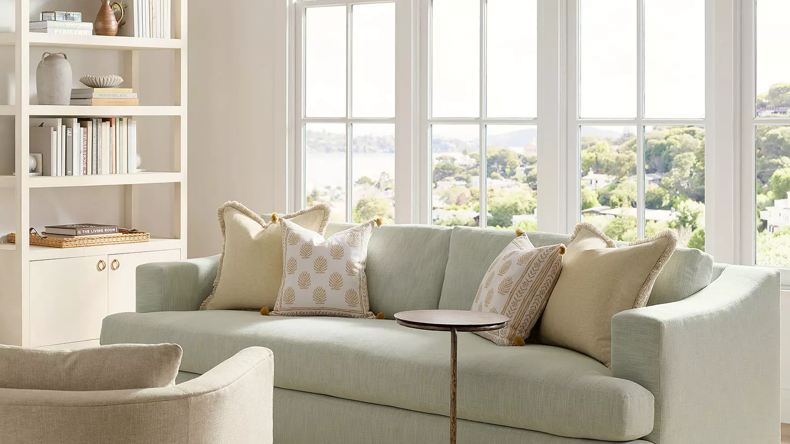 ein Küstenwohnzimmer mit einer grünen Couch mit Kissen darauf