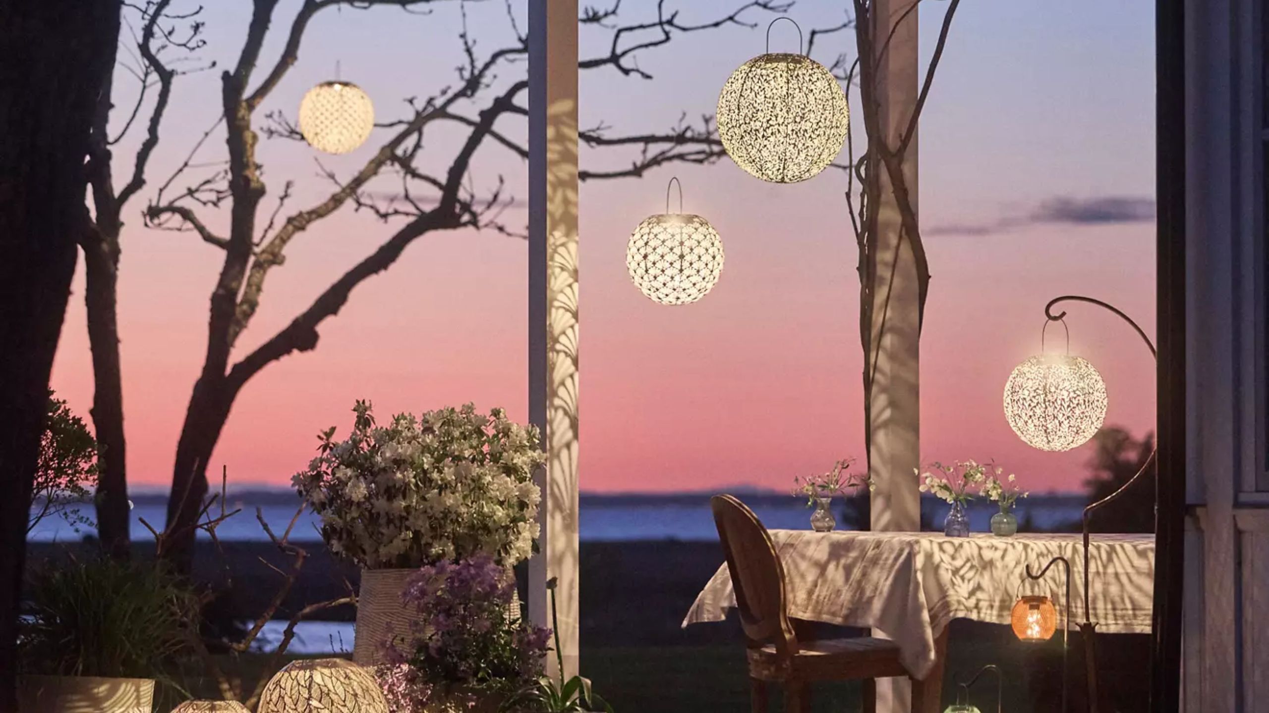 Enchanting outdoor patio at sunset featuring a dining table and several etched-metal, Art Nouveau-inspired solar lights