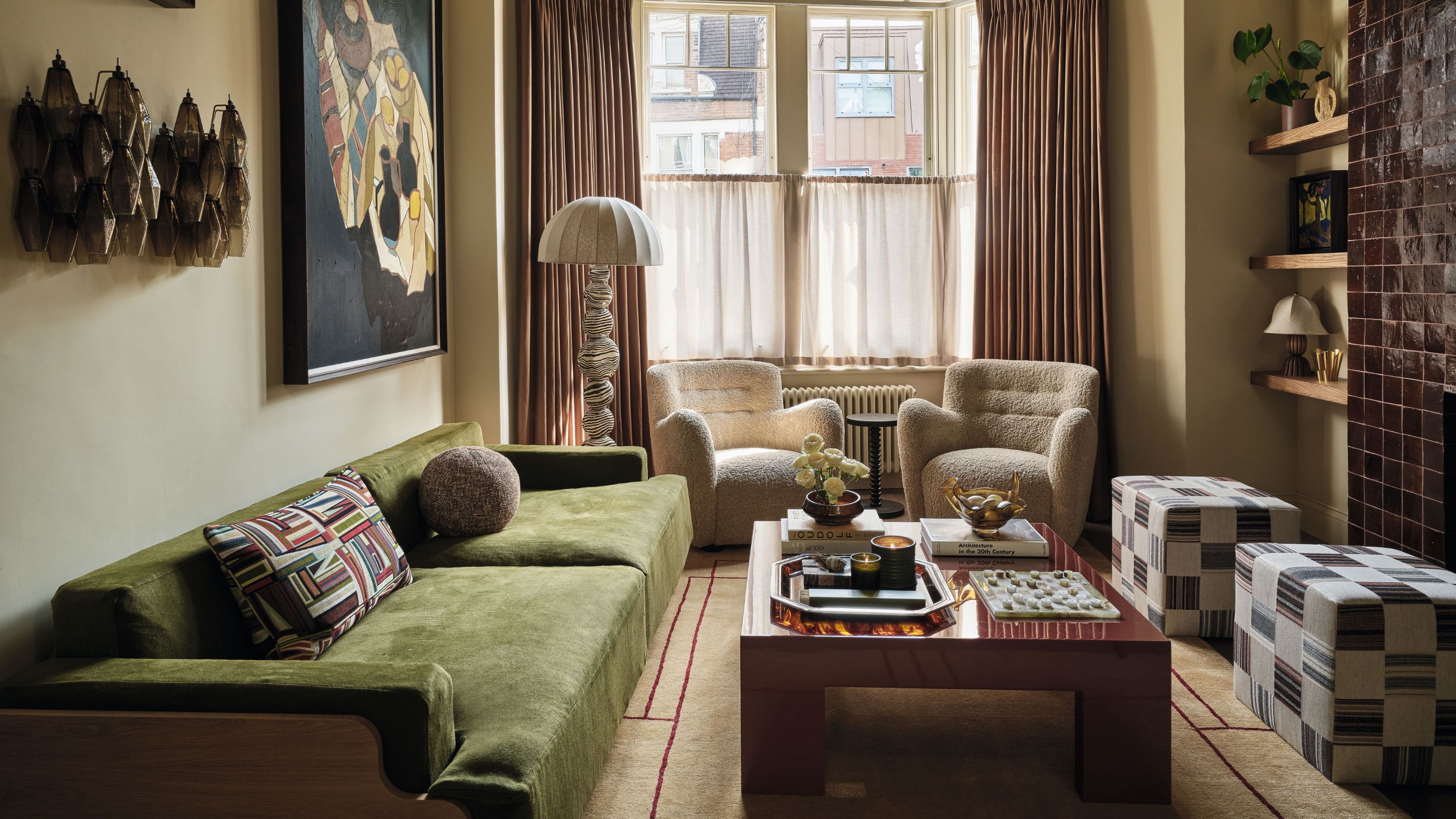 ein Wohnzimmer im viktorianischen Stil mit Erkerfenster mit zwei Schaffellstühlen, einem burgunderroten Kachelkamin, einem grünen Sofa und einem Couchtisch aus Holz