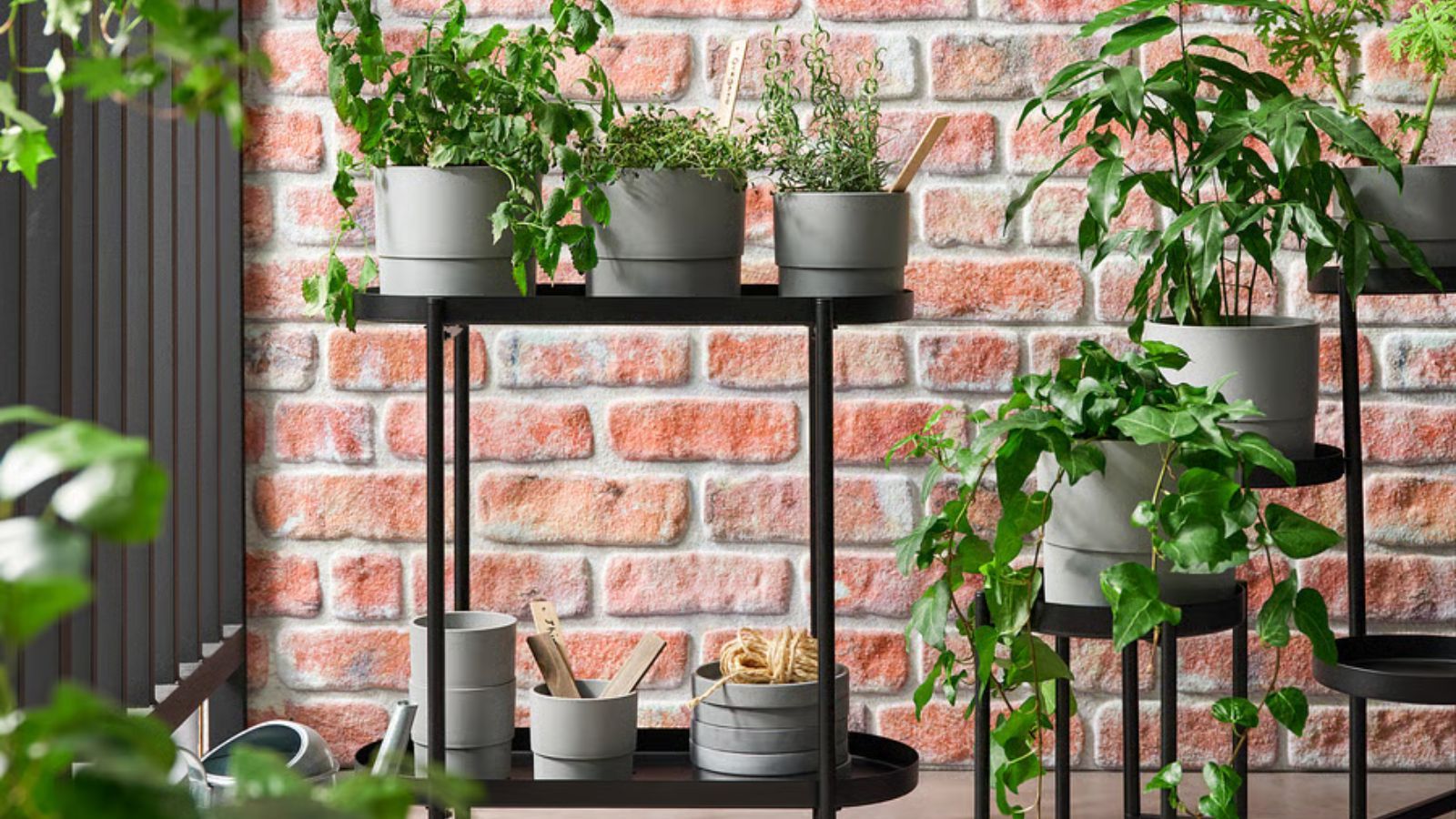 Black steel plant stand with gray plant pots on a balcony