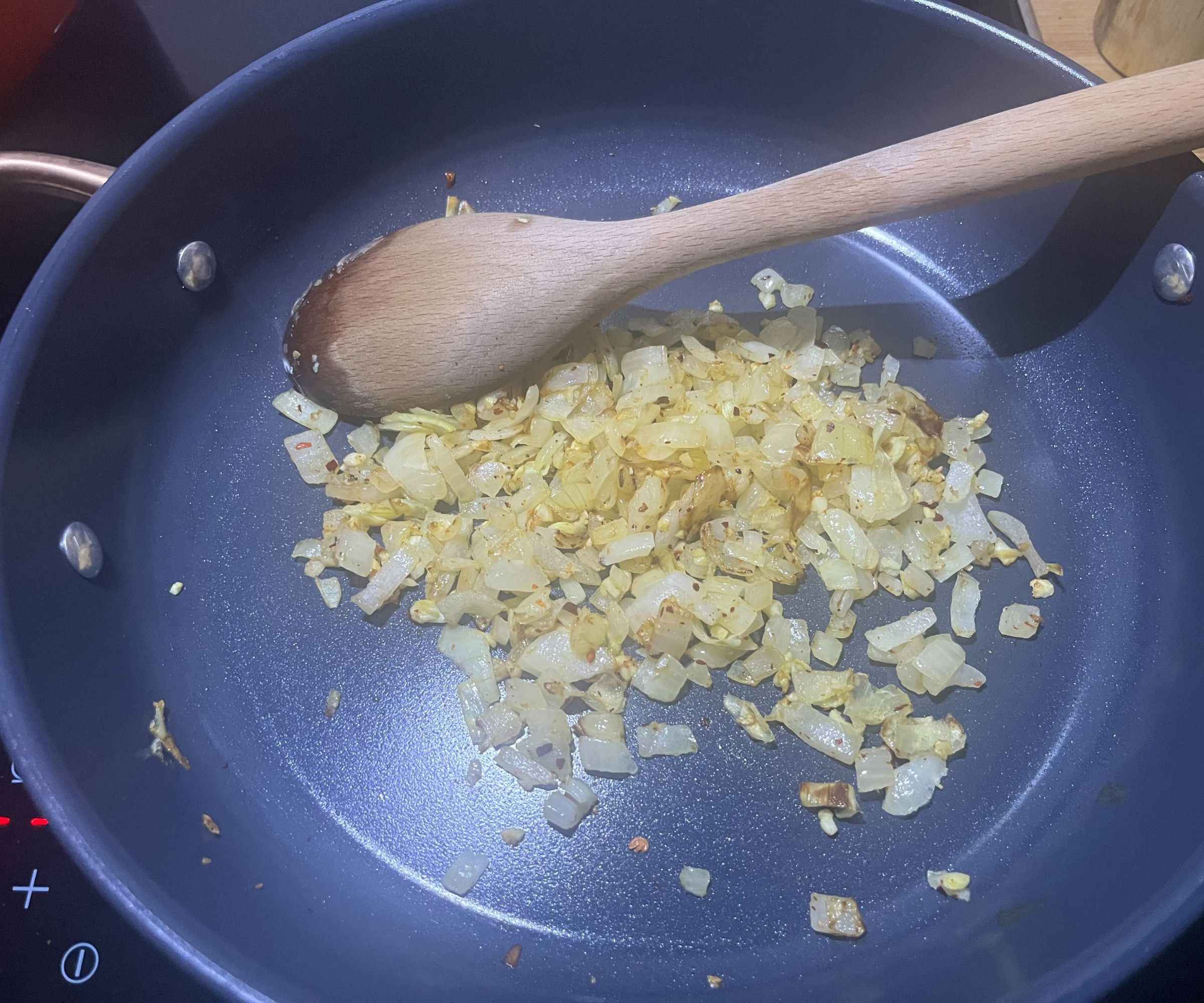 Zwiebeln karamellisieren in einer blauen Keramikpfanne