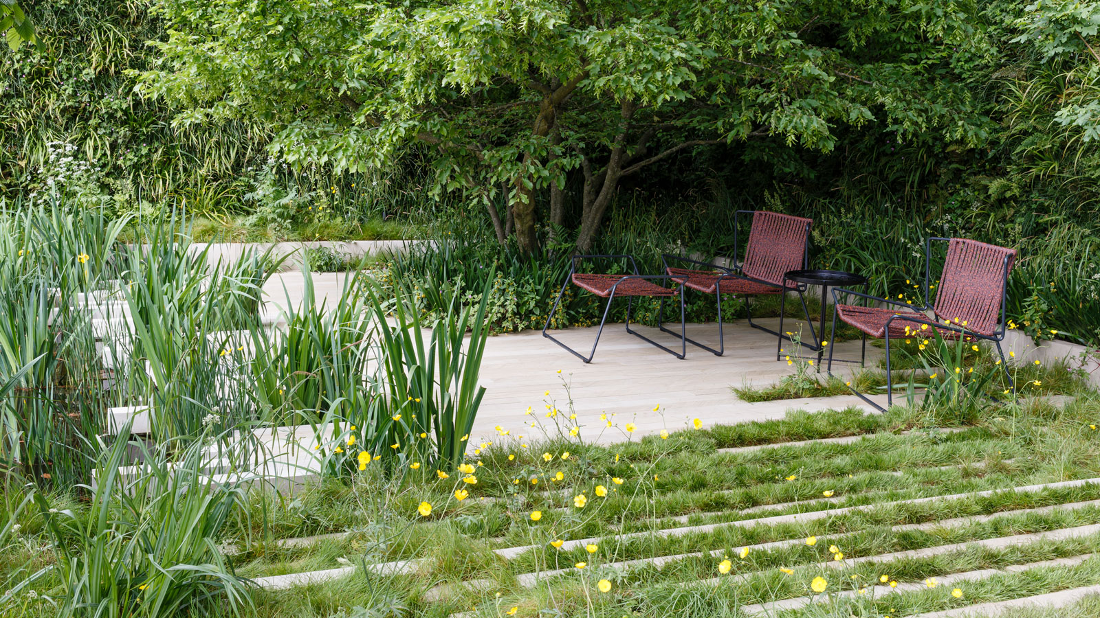 Gartengestaltung mit heller Landschaftsgestaltung und natürlicher Bepflanzung, mit Gartenstühlen und -tisch sowie Bäumen