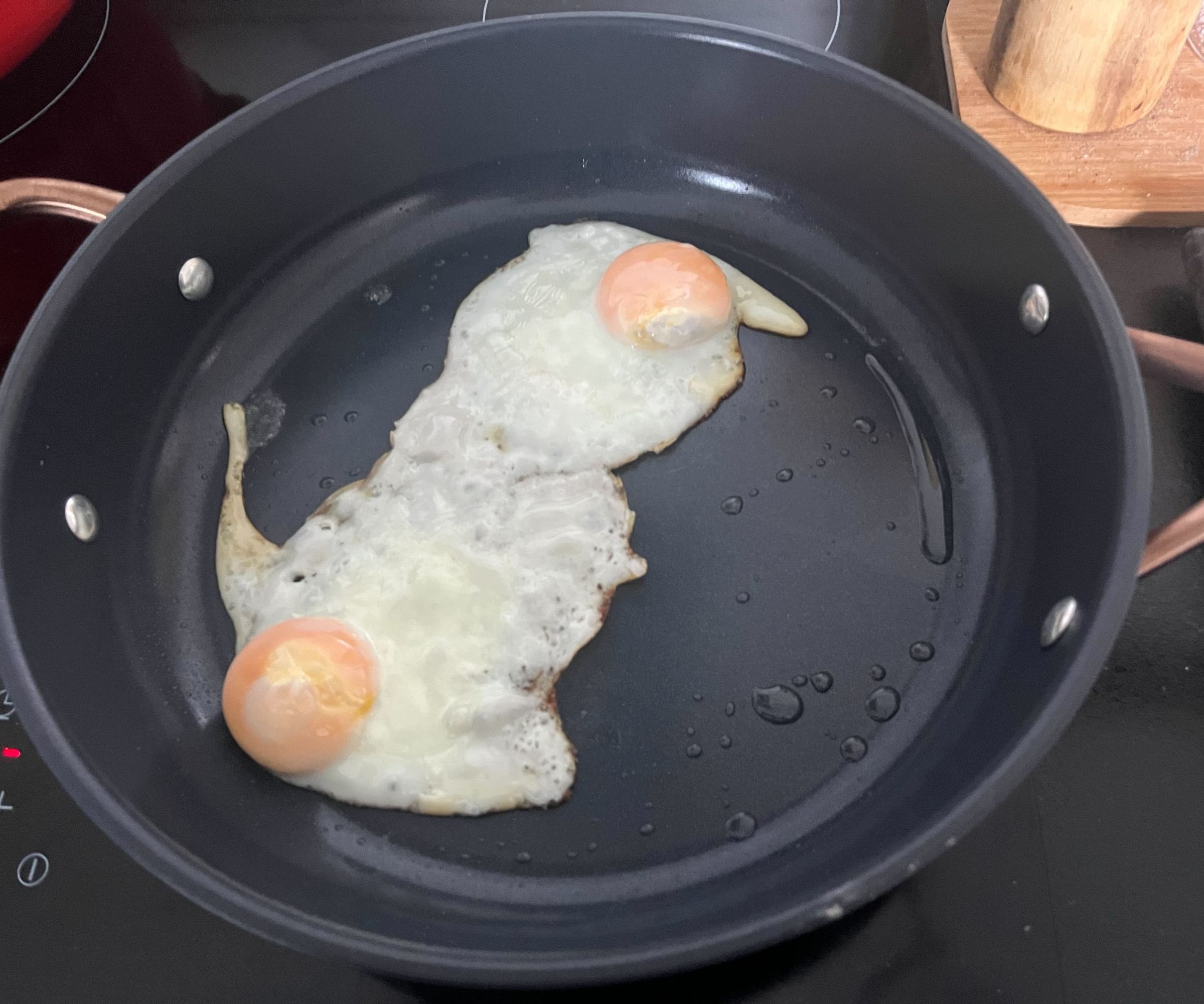 Zwei Eier in einer kleinen blauen Keramikpfanne braten