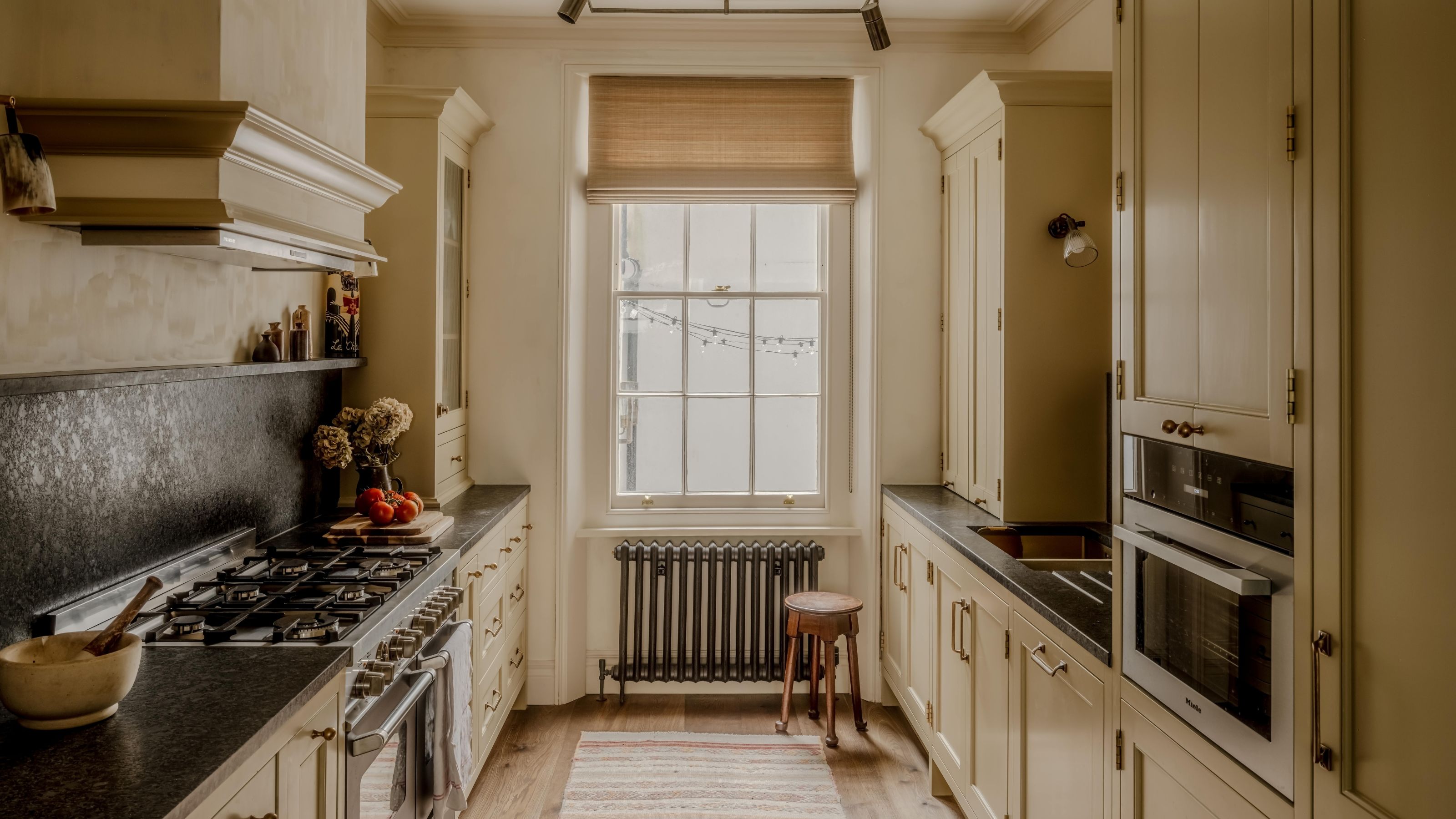 Eine warme, buttergelbe Küche in einem Londoner Stadthaus mit georgianischen Fenstern und dunklen Arbeitsplatten