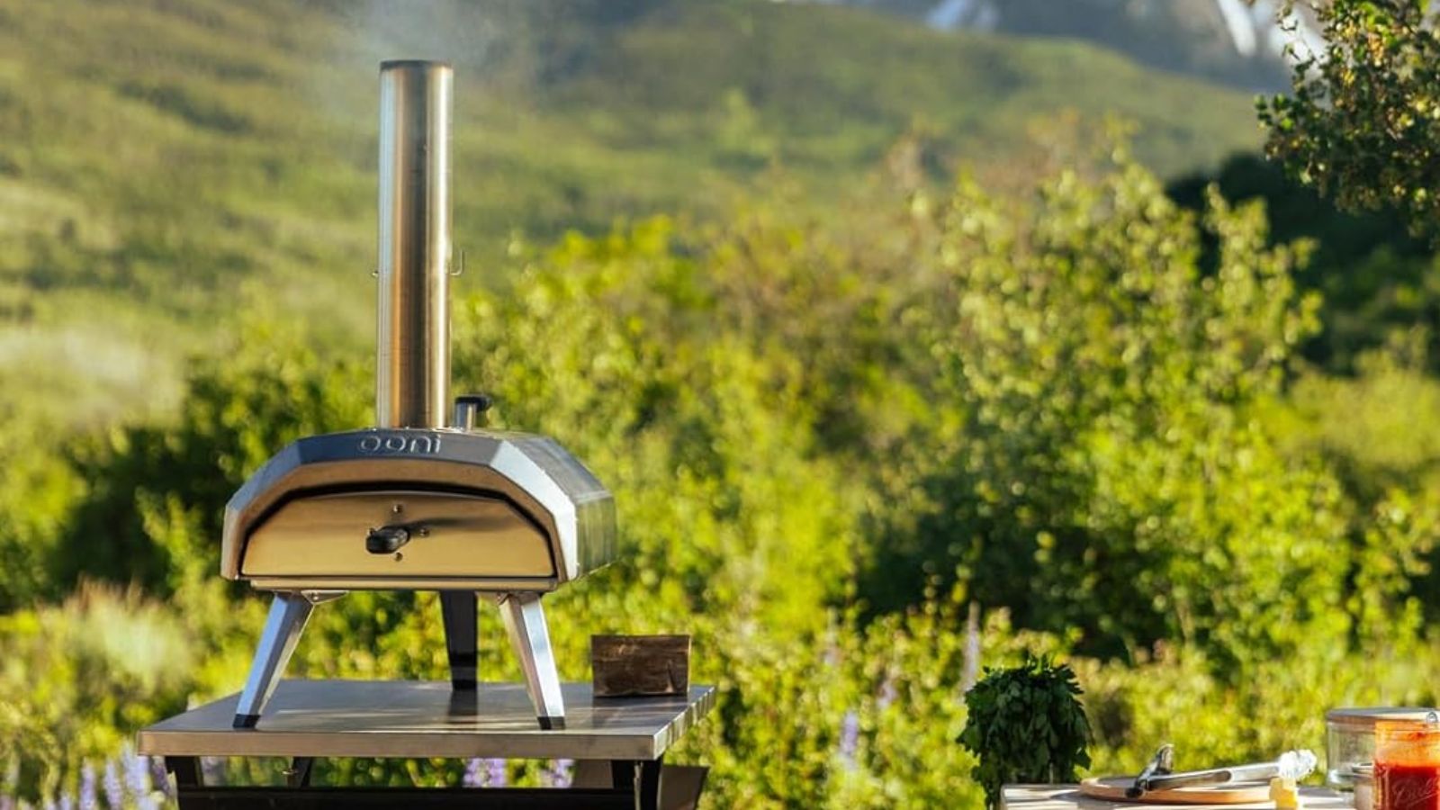 Der Pizzaofen Ooni Karu 12 auf einem Edelstahltisch, draußen, vor einem Berg 