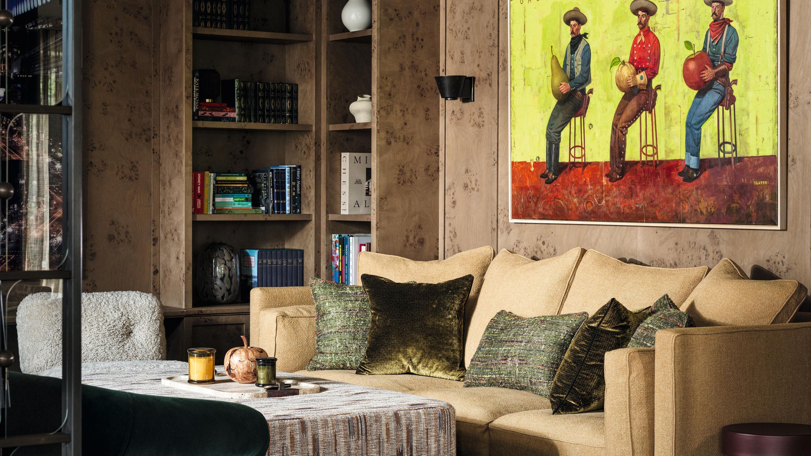 eine mit Wurzelholz verkleidete Sitzecke mit eingebauten Regalen, eine beige Couch und ein Cowboy-Gemälde an der Wand