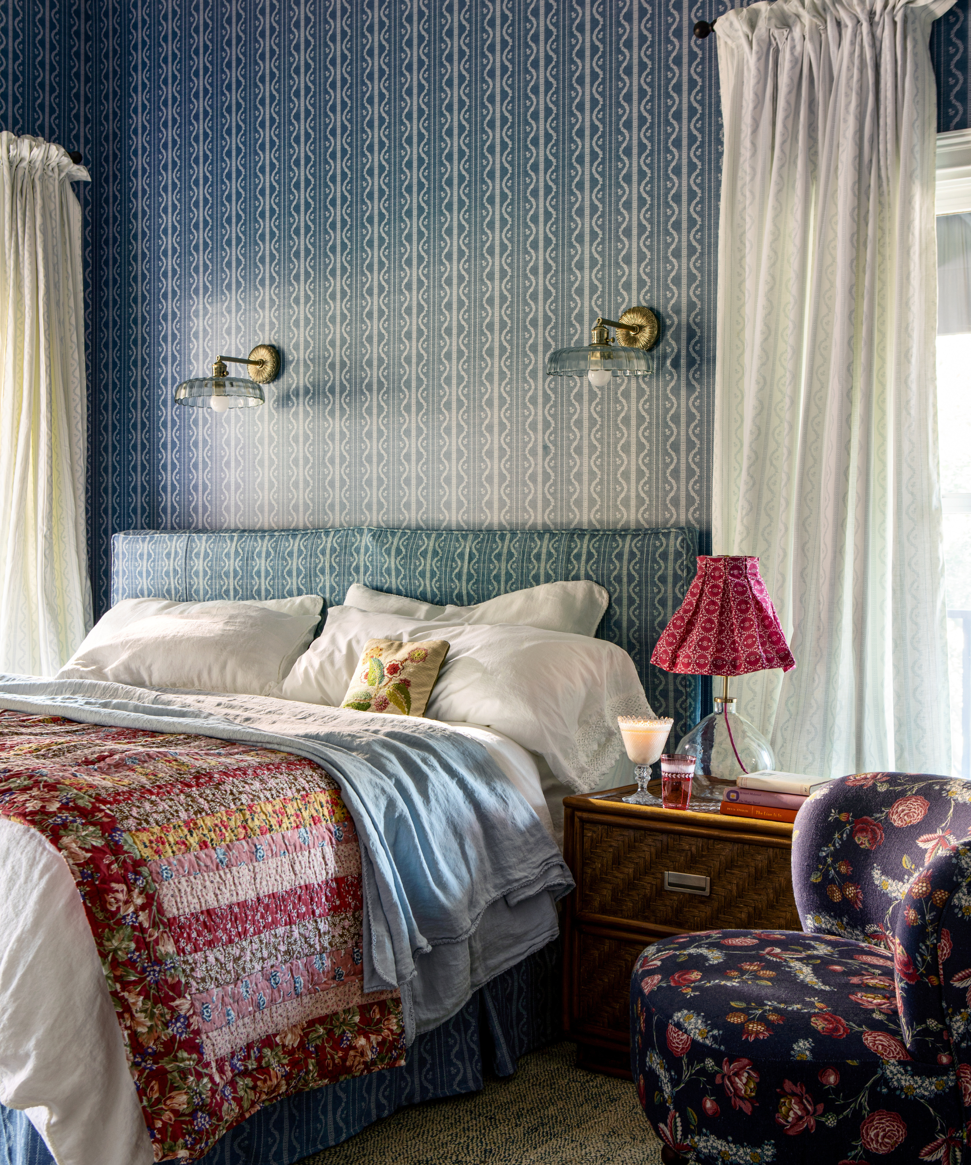 ein gemütliches Schlafzimmer mit blau tapezierten Wänden, einem Etagenbett und einem dunkelblauen Stuhl mit Blumenakzent