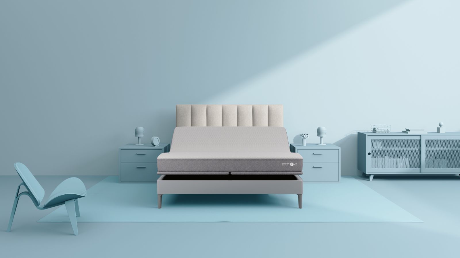 Matratze „Sleep Number c2“ auf einem hellgrauen Bett mit geriffeltem Kopfteil vor einer hellblauen Wand. Die Nachttische, der Stuhl, der Schrank und die Accessoires sind alle im gleichen Blauton gehalten.