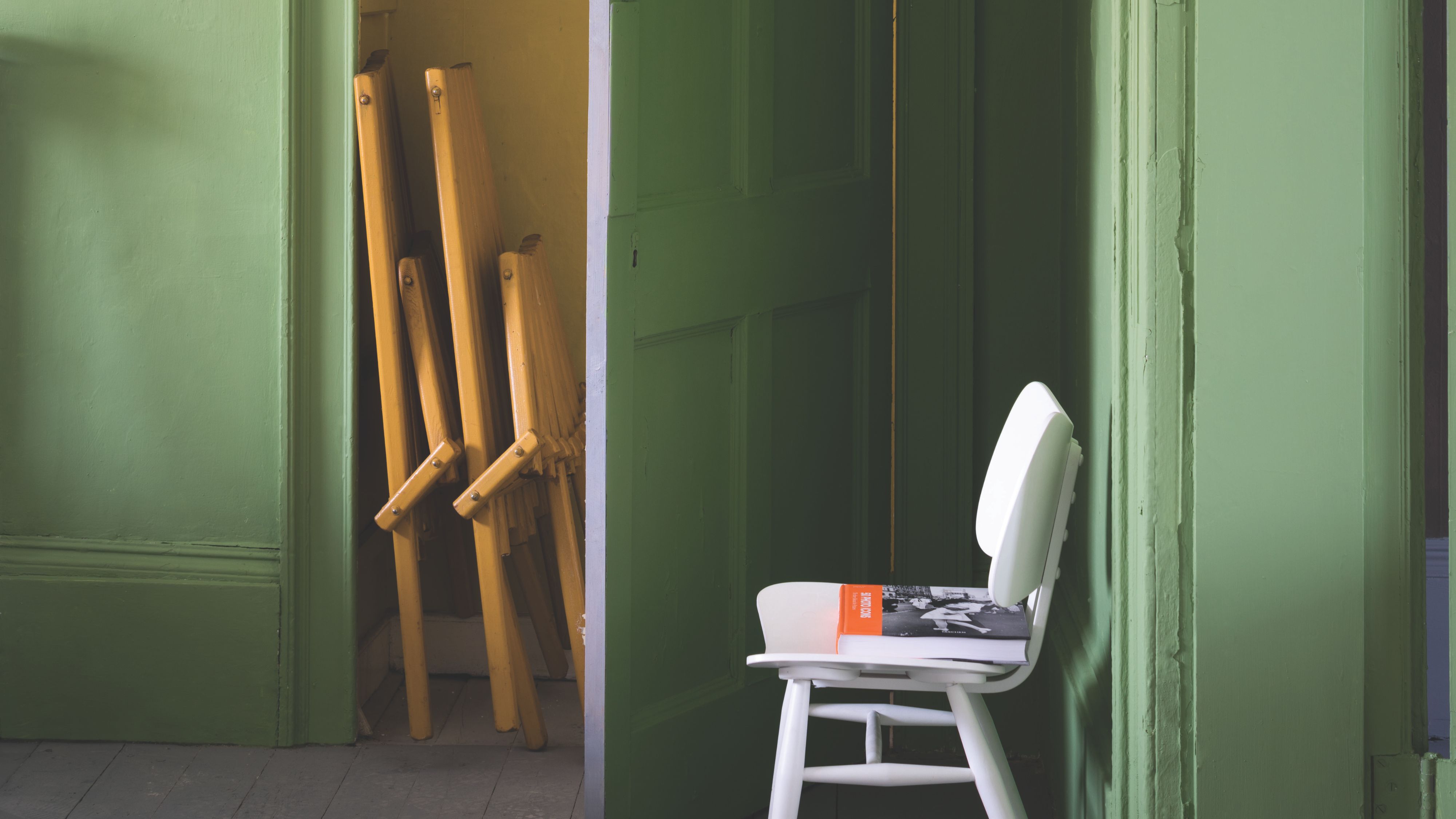 Abstellraum mit Chartreuse-Bemalung, zusammengeklappten Möbeln und einem weißen Stuhl im Mid-Century-Stil