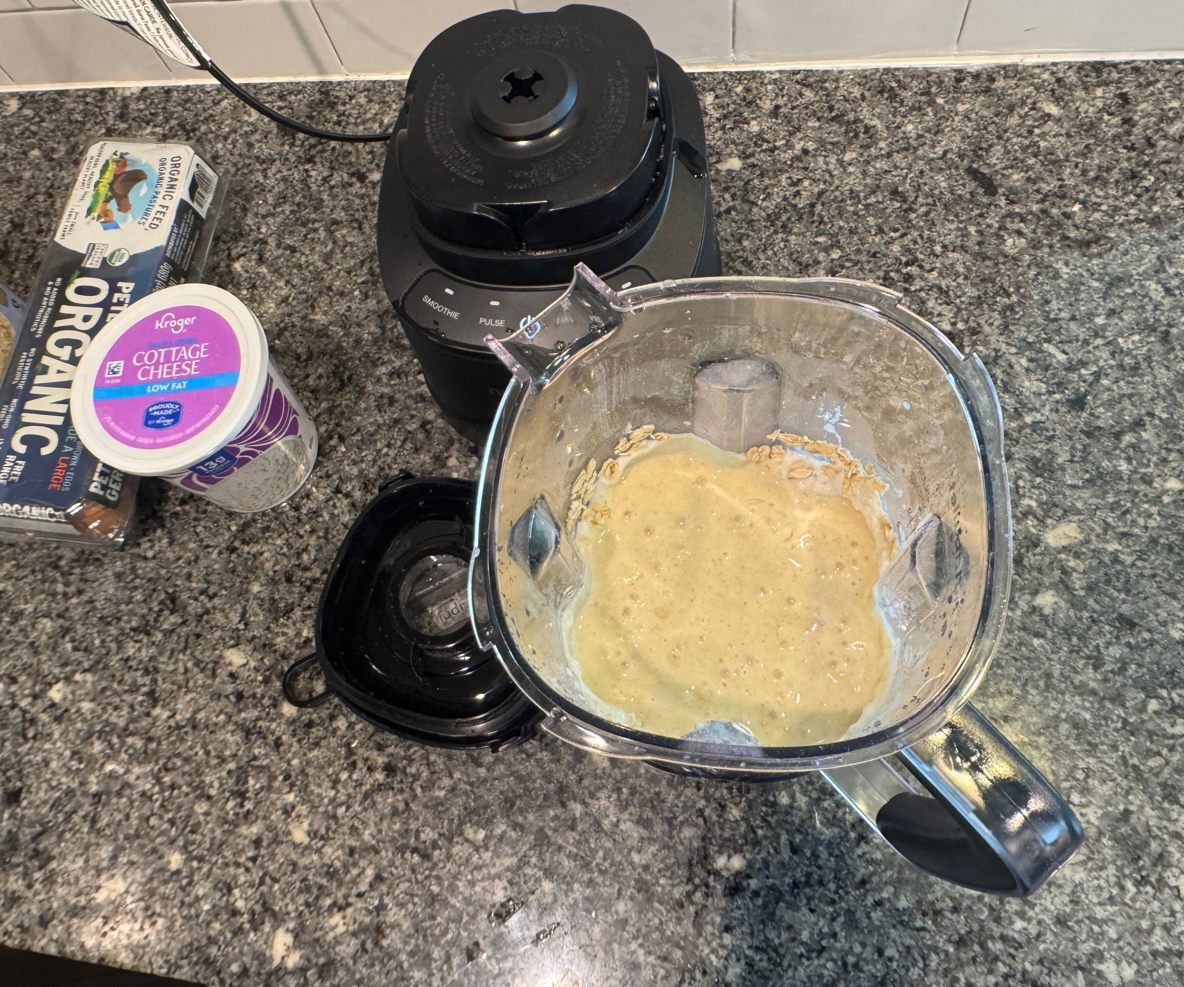 Den Teig in einem durchsichtigen Mixerkrug auf einer Küchenarbeitsplatte aus Stein aufschlagen.