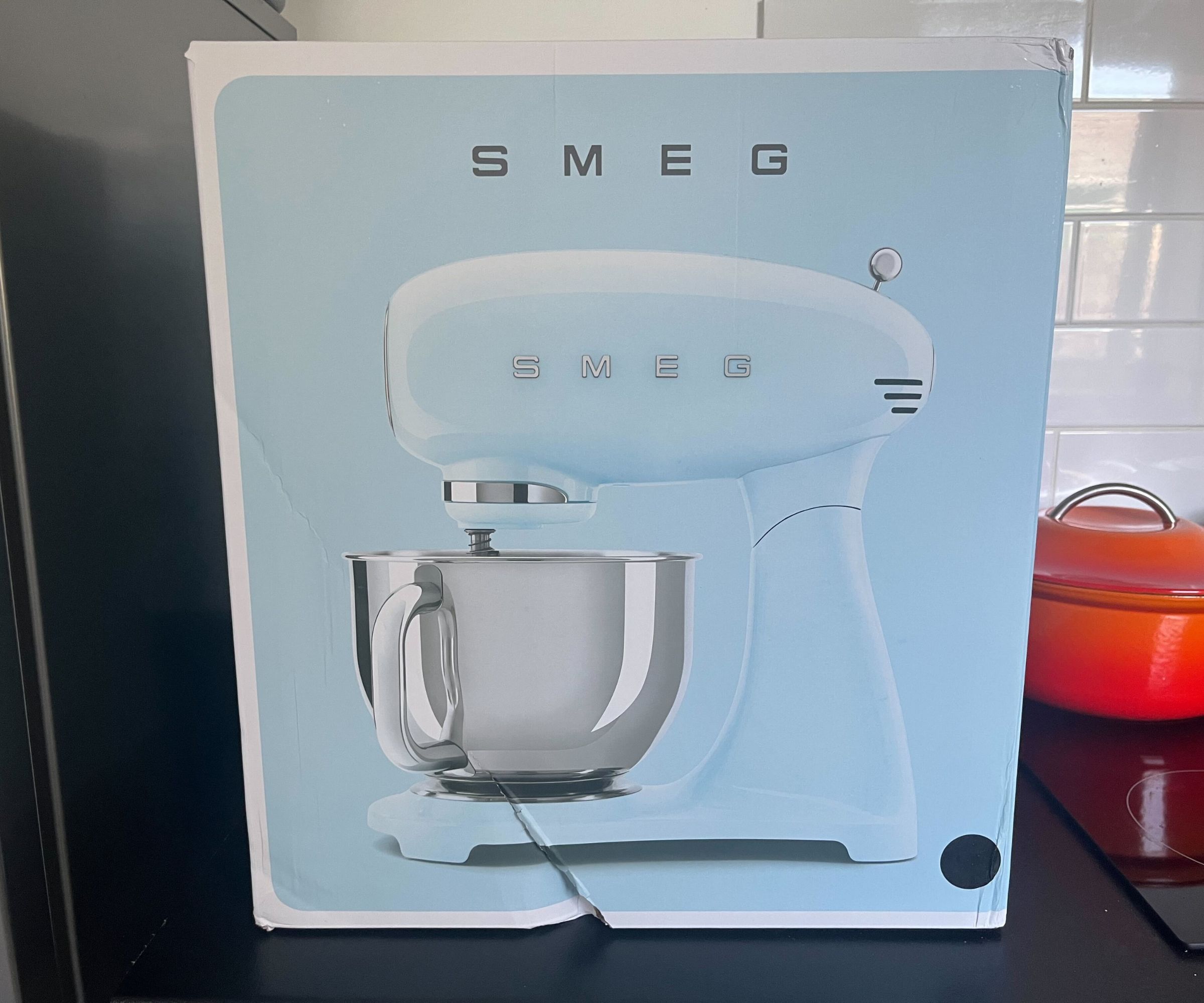 Eine babyblaue SMEG Forte Küchenmaschine auf einer schwarzen Küchentheke