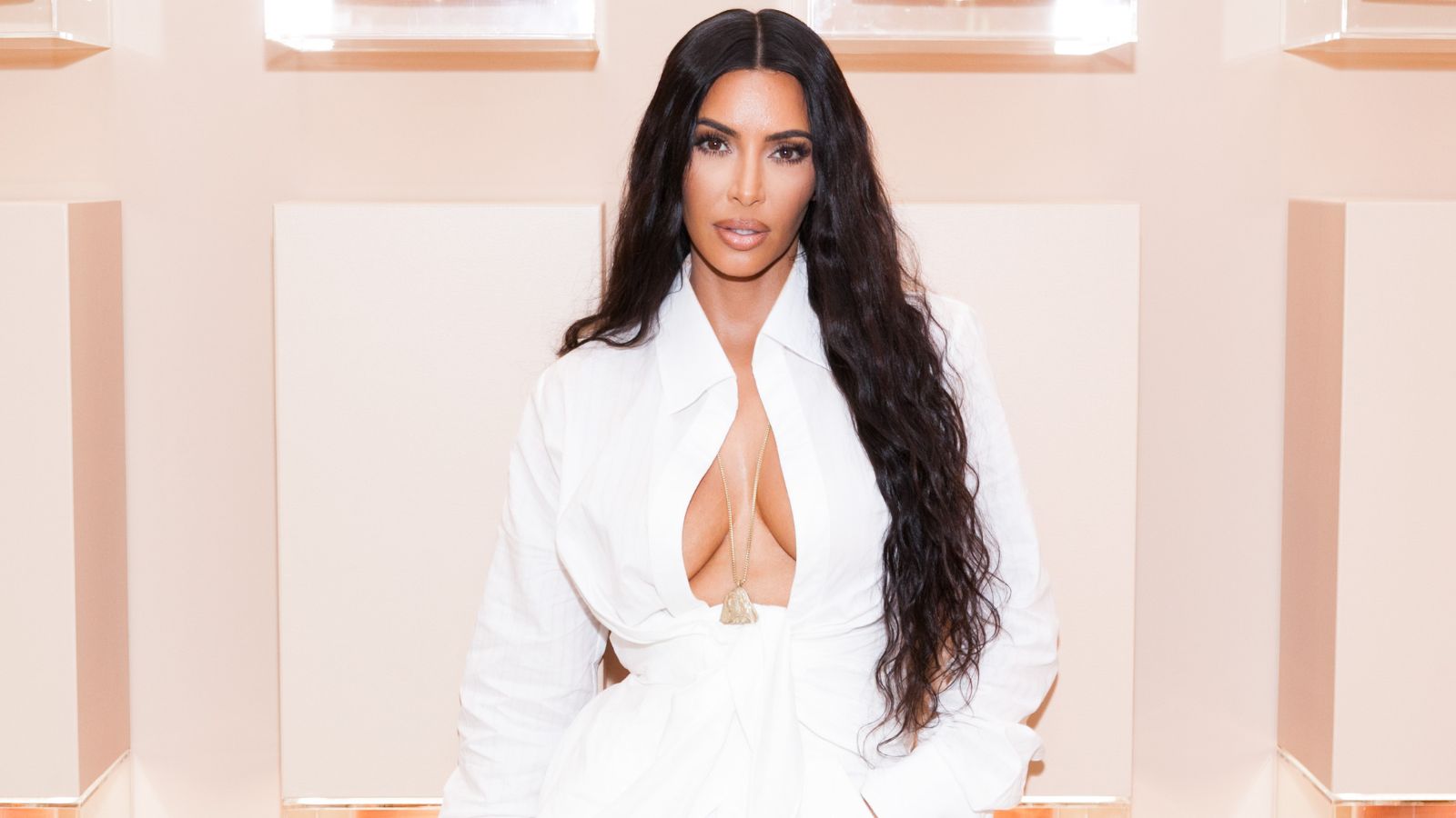 Kim Kardashian in einem weißen Hemd auf rosa Hintergrund