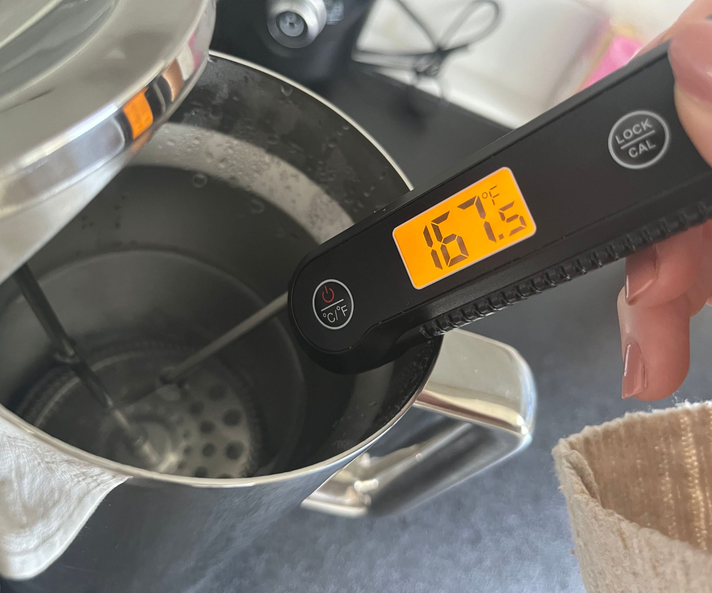 Ein digitales Thermometer, das die Wassertemperatur in einer Kaffeepresse aus Edelstahl misst. Es zeigt 167F