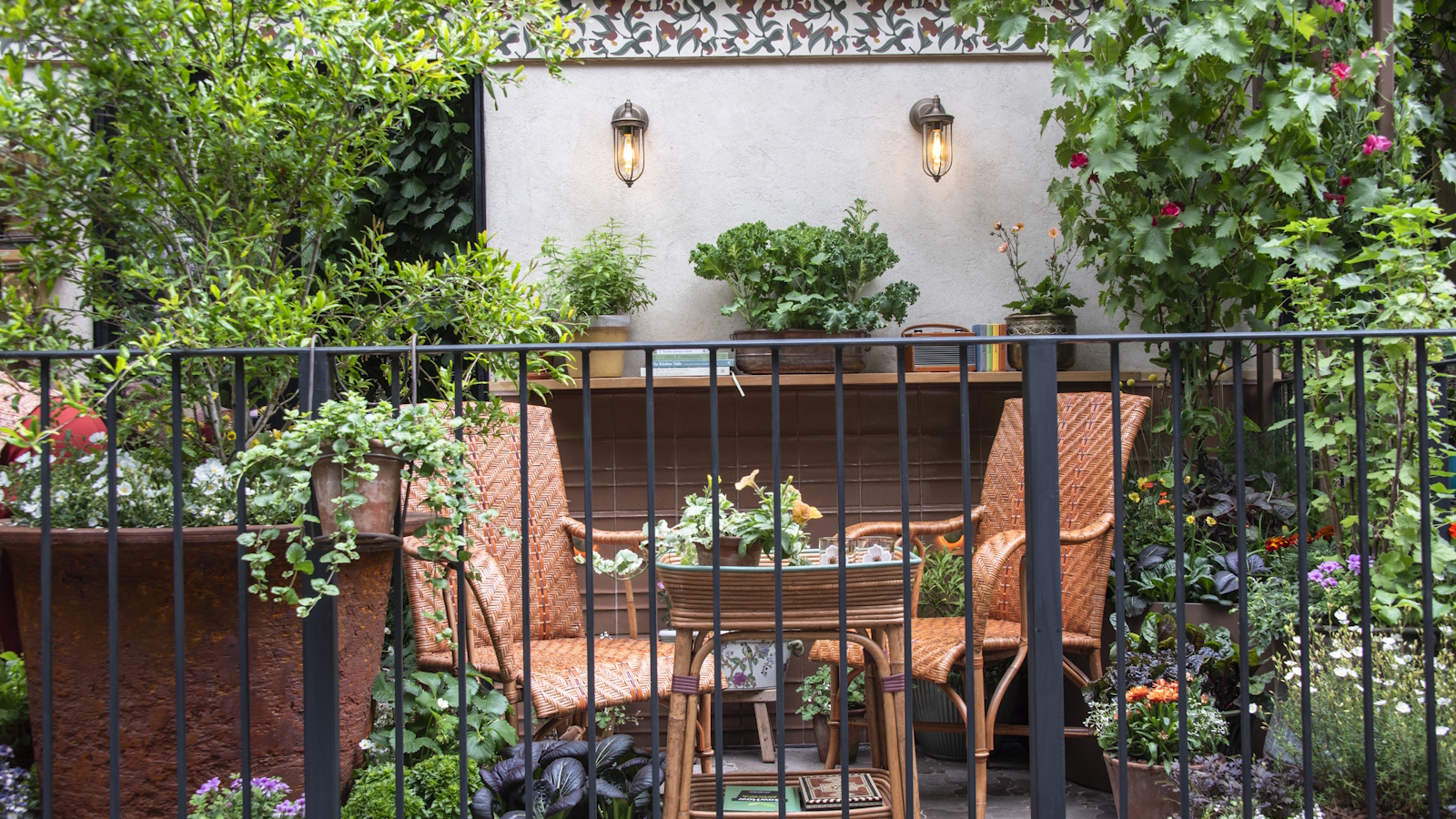 Zwei Stühle und ein Tisch, umgeben von Sträuchern und Blumen in Töpfen auf einem Balkon bei der RHS Chelsea Flower Show