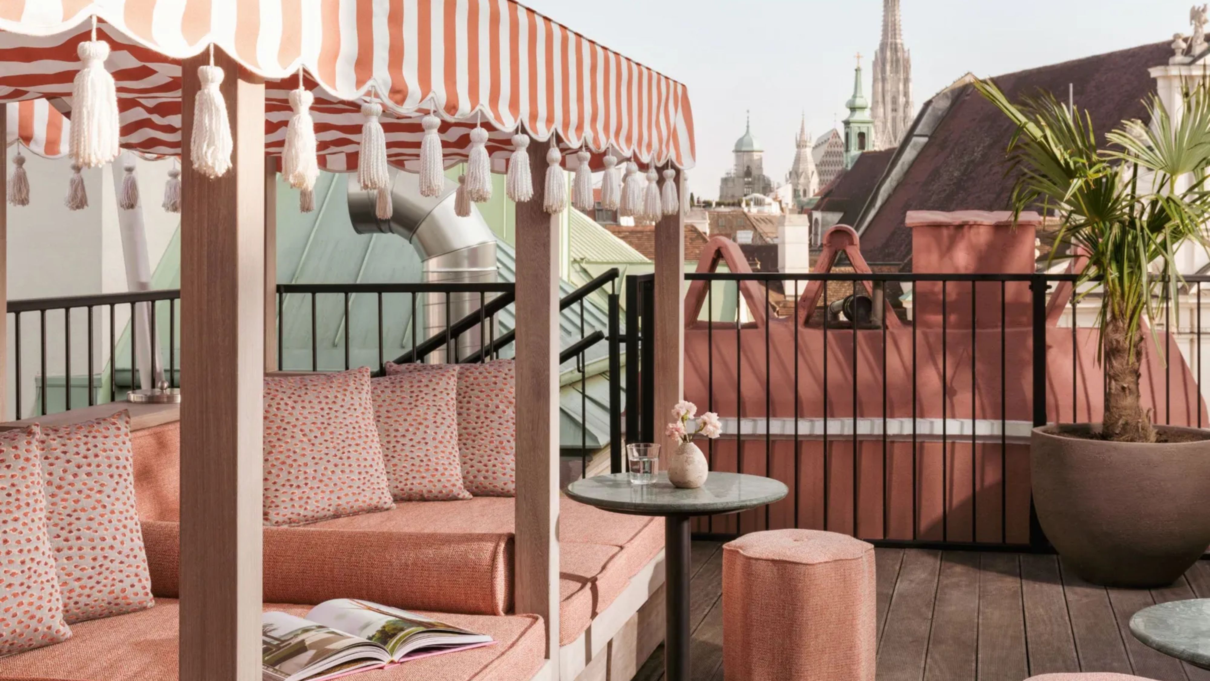Flamingorosa gepolsterte Terrassensitzgruppe mit gestreiftem Vordach mit Quastenakzenten und kleinem Terrassentisch