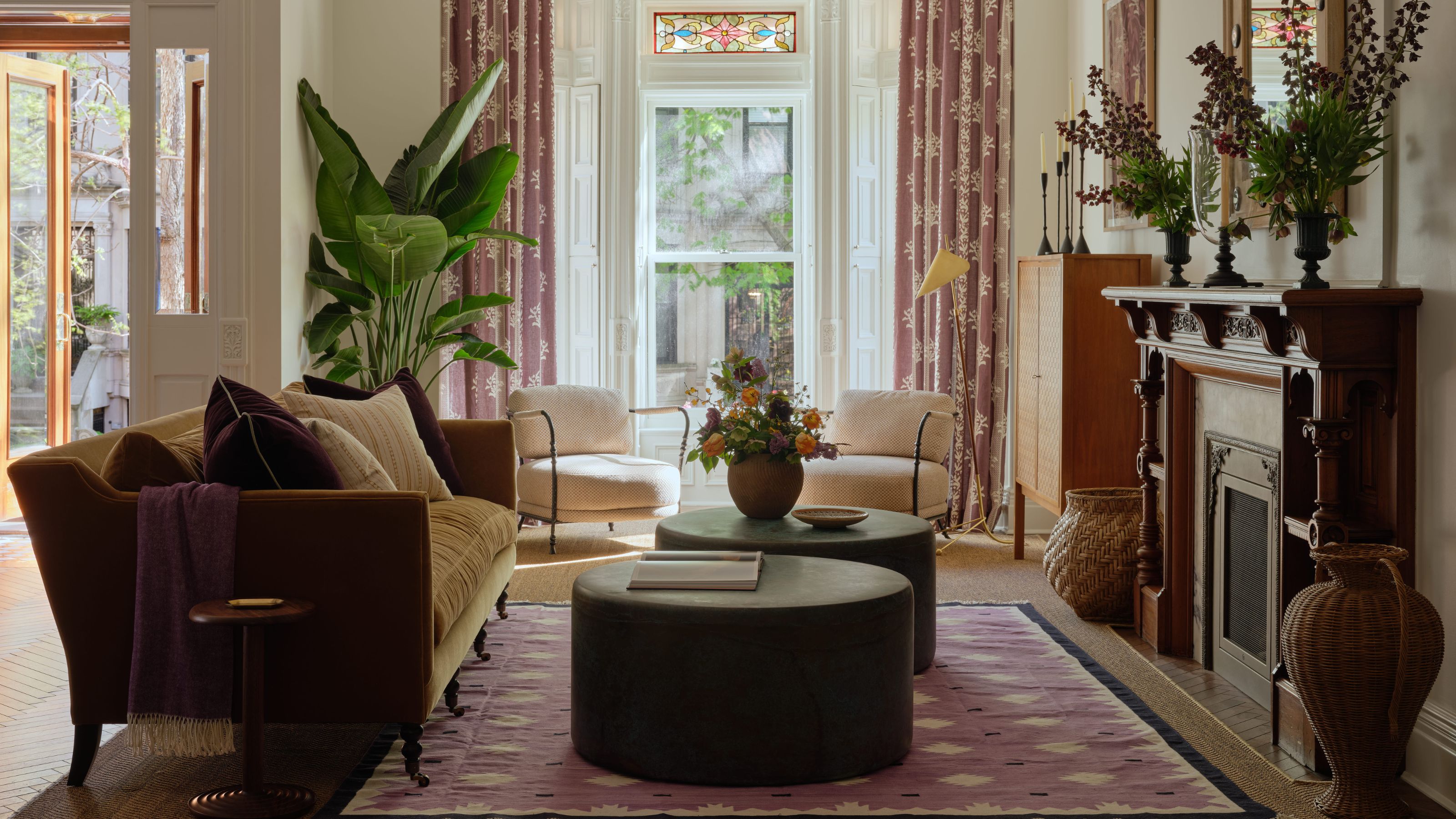 Das Wohnzimmer eines Stadthauses in Park Slope in New York mit riesigem Erkerfenster mit Buntglas, antikem Holzkamin und modernen Möbeln