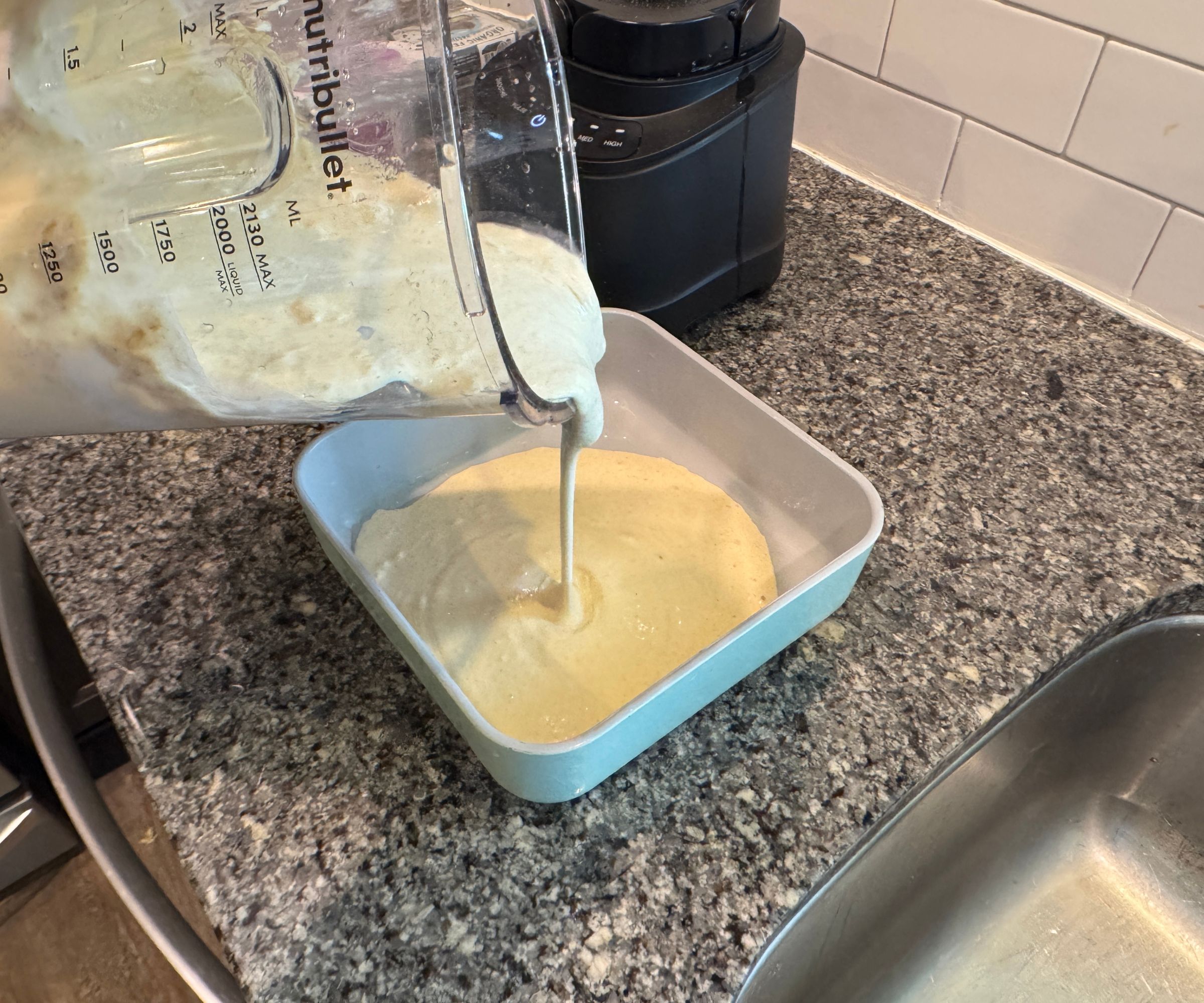 Den Teig aus einem Mixerkrug in eine quadratische Kuchenform gießen.