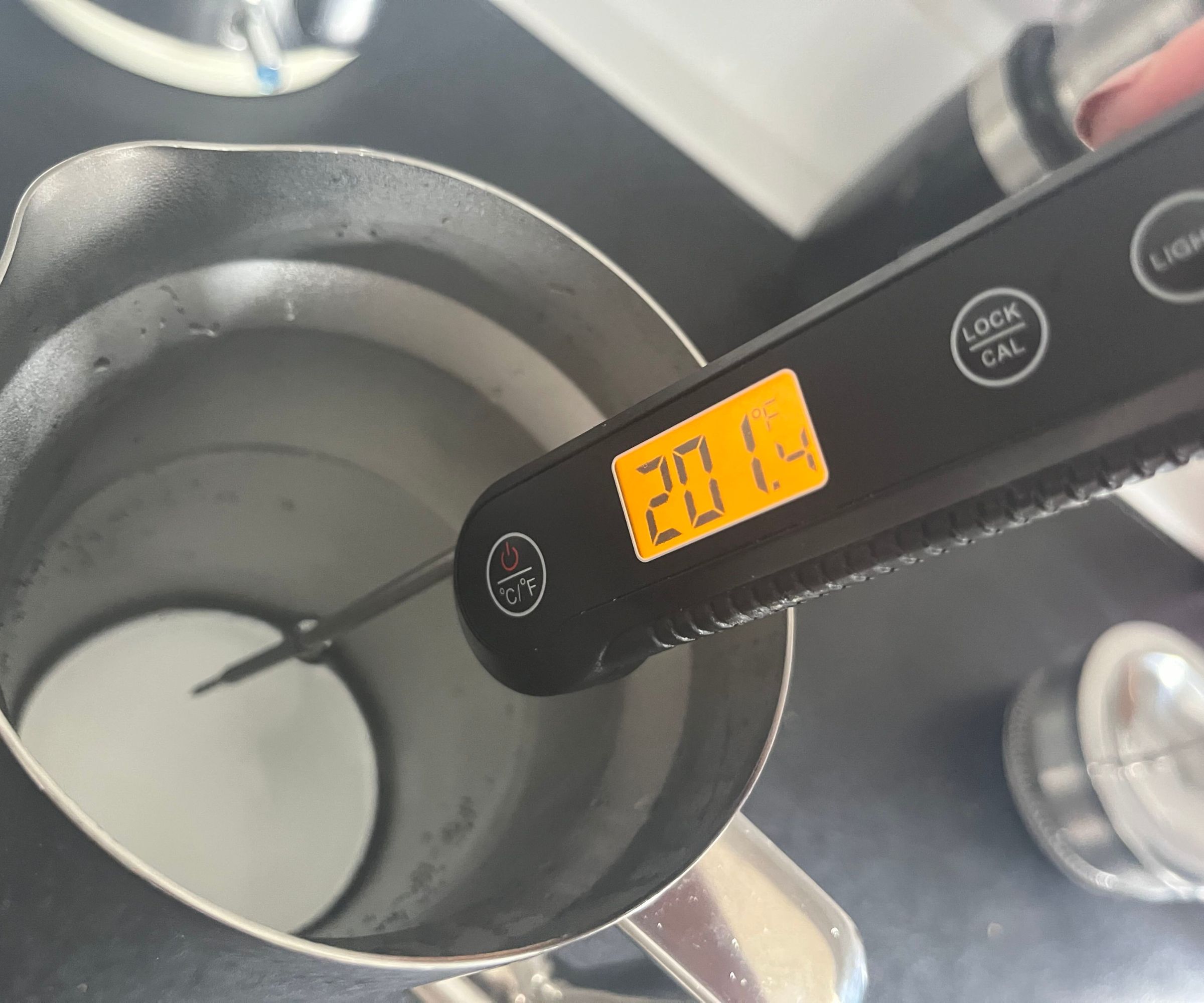 Ein digitales Thermometer, das die Wassertemperatur in einer Kaffeepresse aus Edelstahl misst. Es zeigt 201F