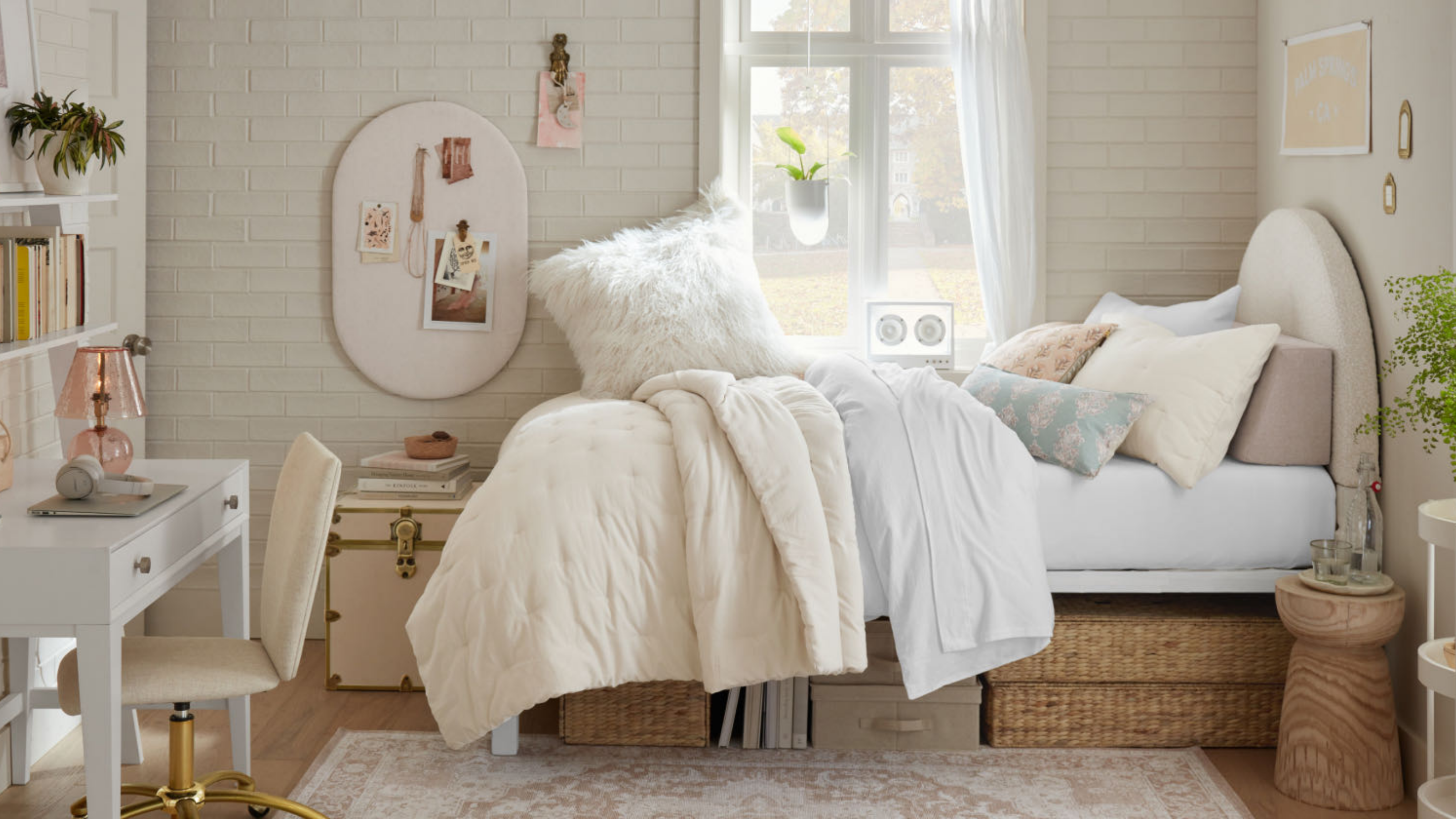 ein Schlafsaal mit einer weißen Backsteinwand, einem Bett mit mehreren Kissen oben und Stauraum darunter und einem Schreibtisch auf der linken Seite