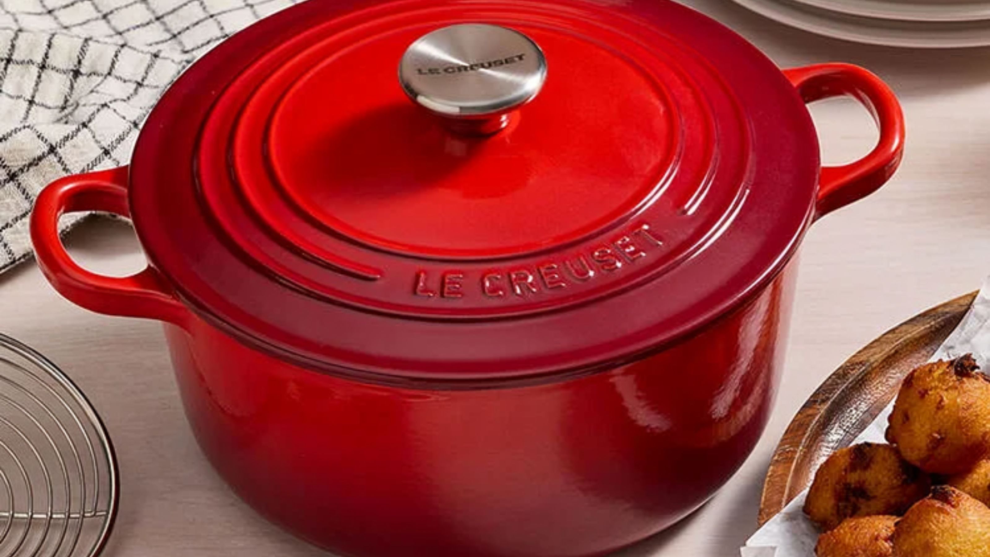 Ein roter Le Creuset Dutch Oven auf einem Küchentisch, mit silbernem Griff. 