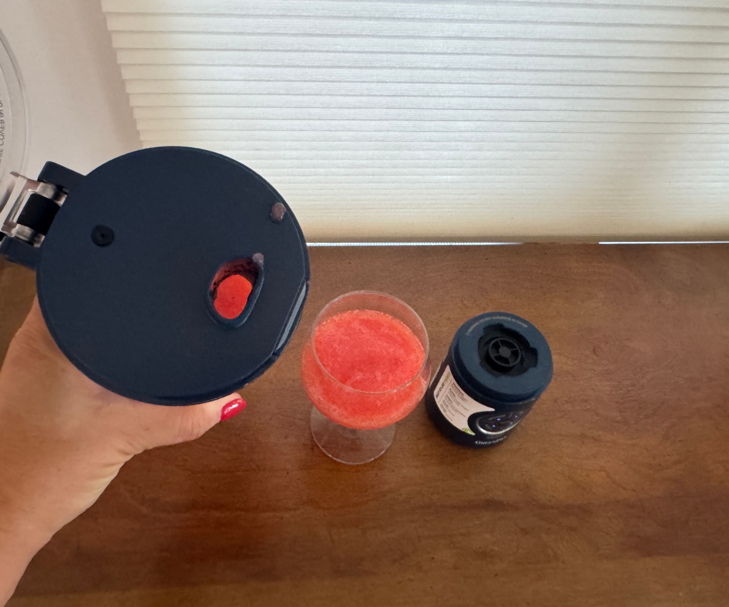 Eine Nahaufnahme des Trinkauslaufs, nachdem ein rosafarbenes Getränk aus dem tragbaren Mixer in ein Glas gegossen wurde.