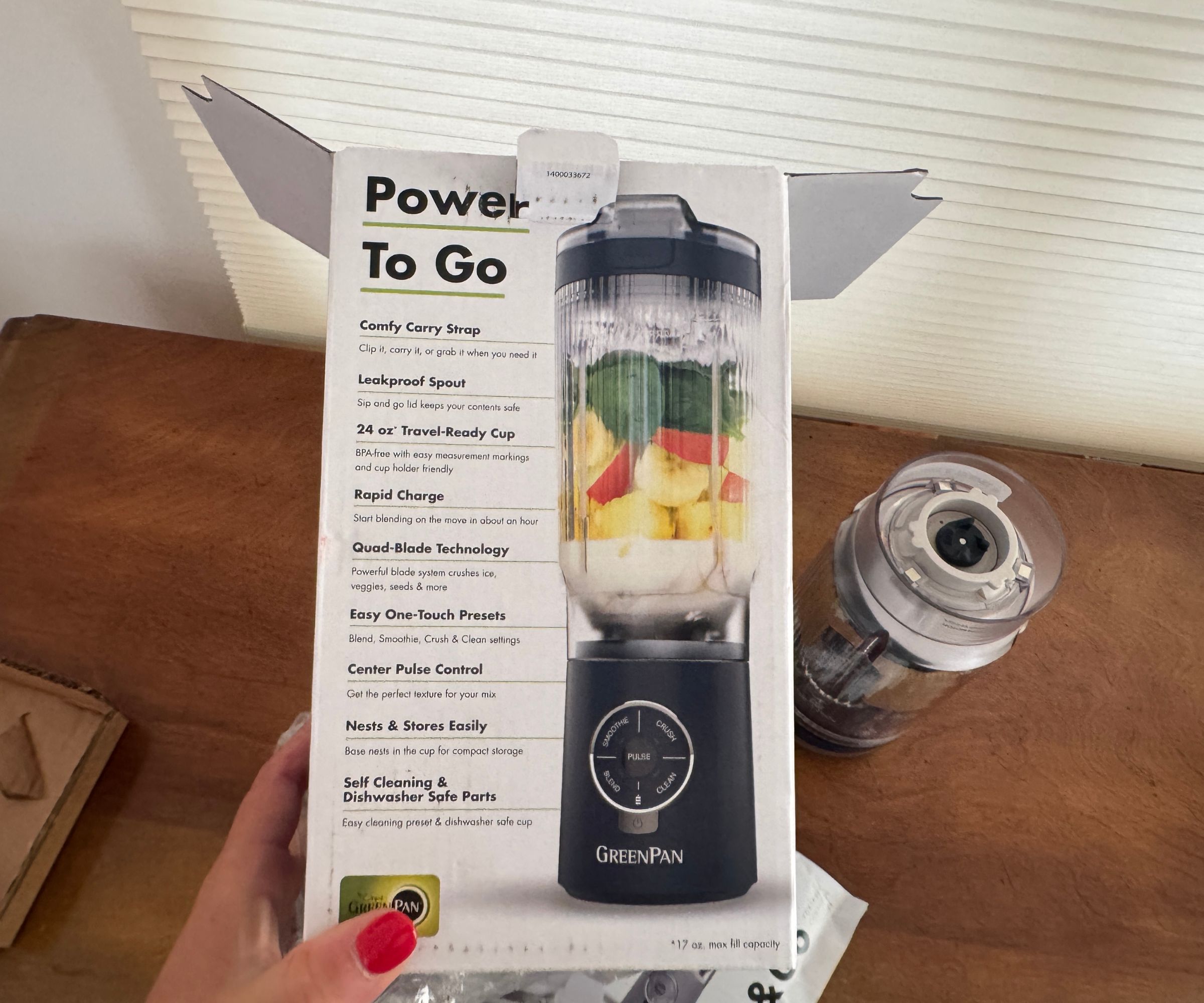 Die weiße Box für den tragbaren Mixer GreenPan Spin & Go wird über einen Holztisch gehalten.