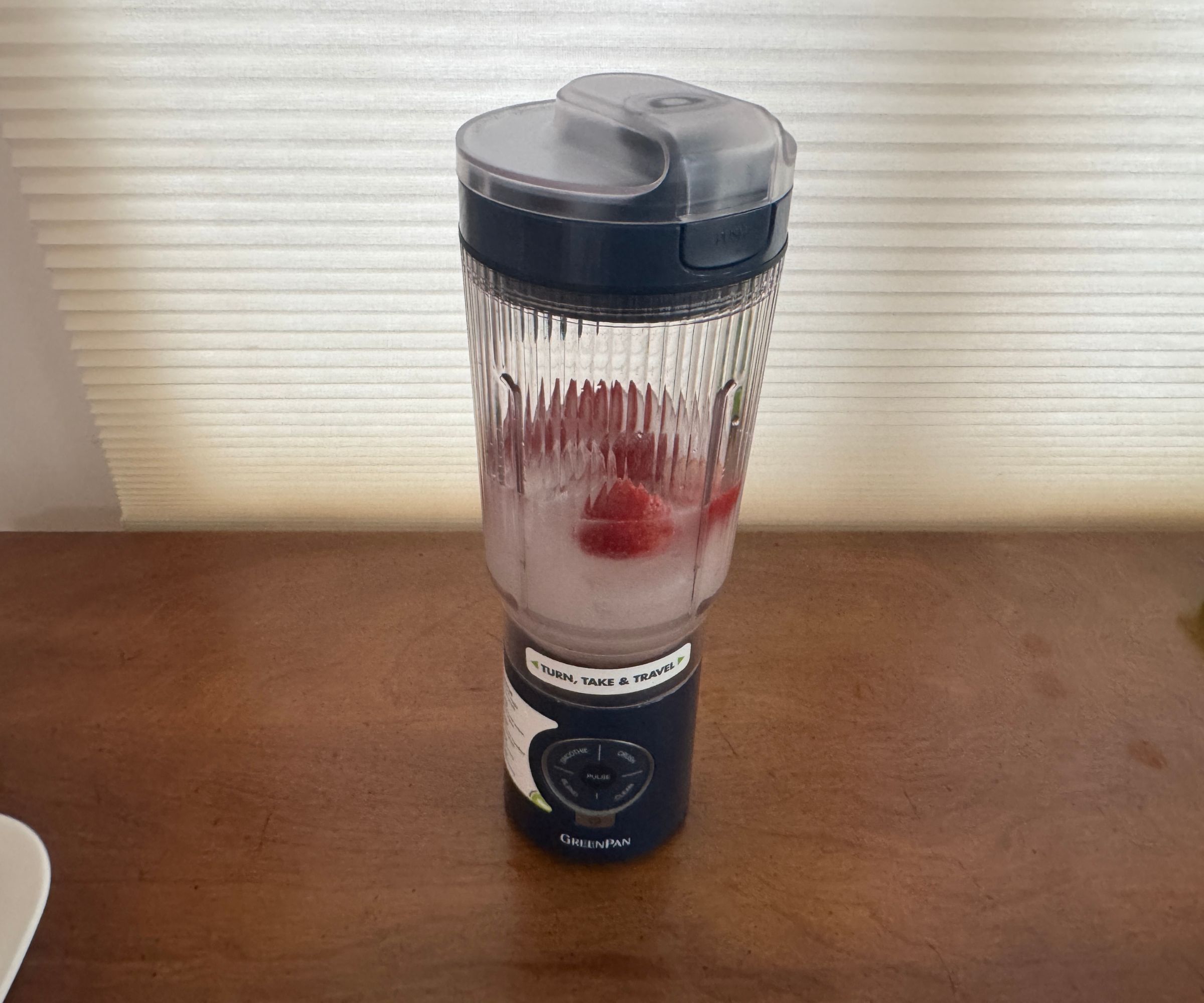 Wasser und Erdbeeren in einem schwarzen tragbaren Mixer.