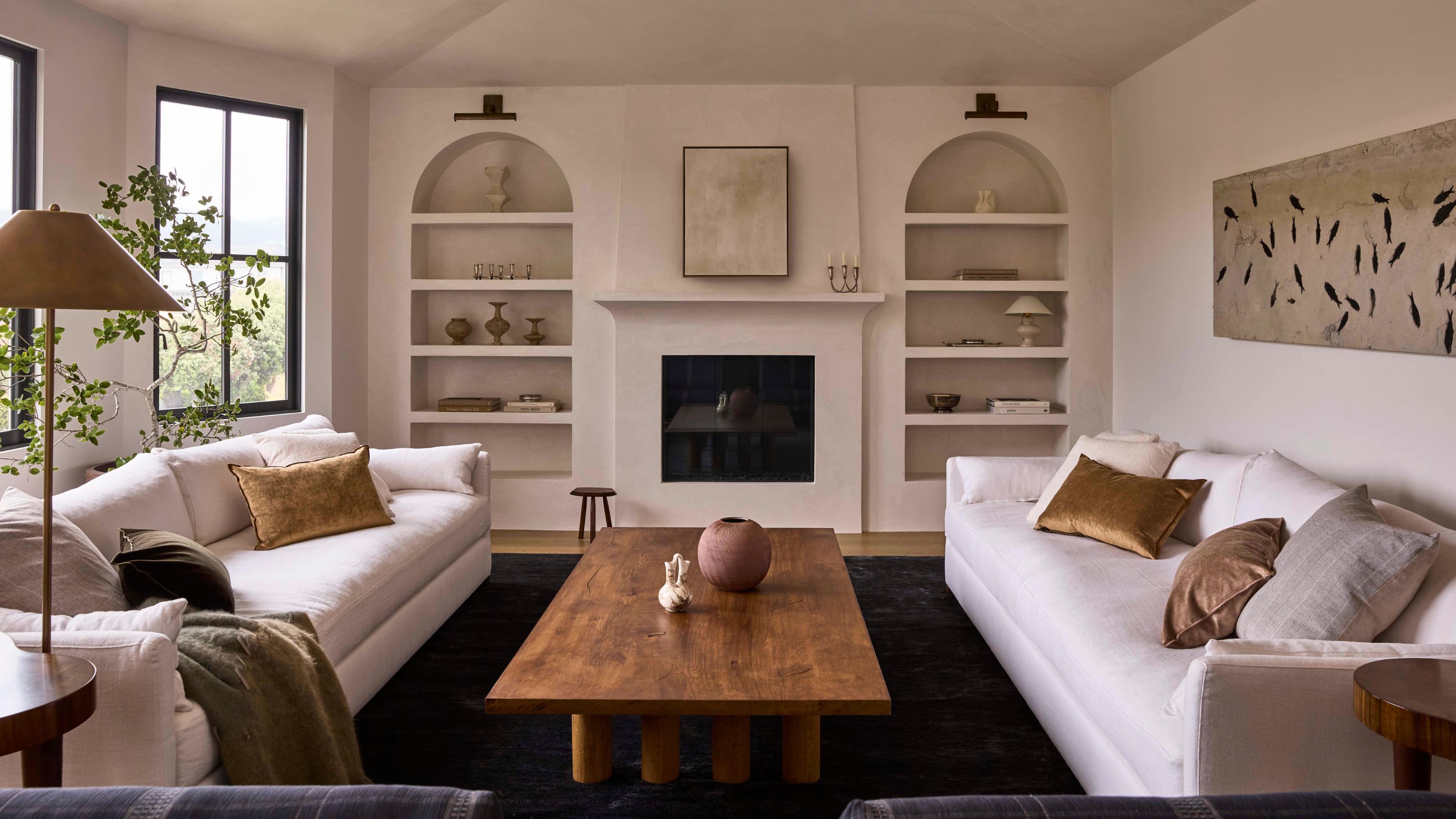 ein großes, neutrales Wabi-Sabi-Wohnzimmer mit gewölbten Bücherregalen, Leinensofas und einem warmen Couchtisch aus Holz