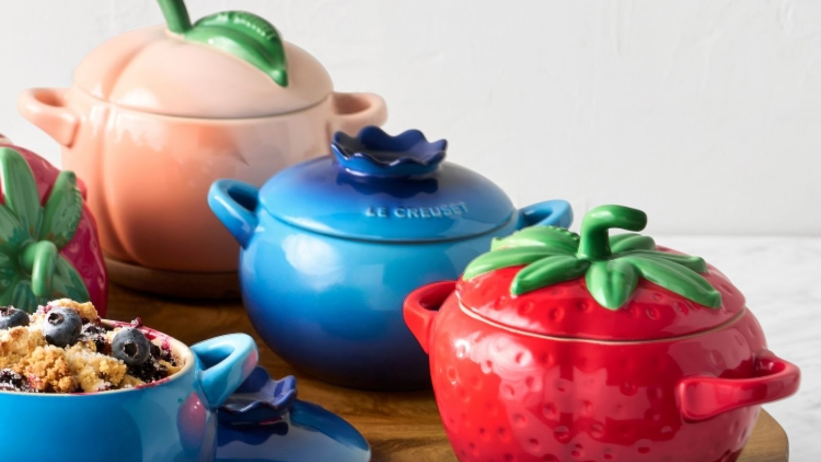 Ein Set aus drei Koketten von Le Creuset in Form einer Erdbeere, einer Blaubeere und eines Pfirsichs 