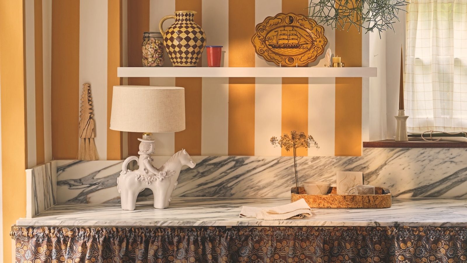 A striped yellow kitchen with a playful cowboy lamp on the marble countertop