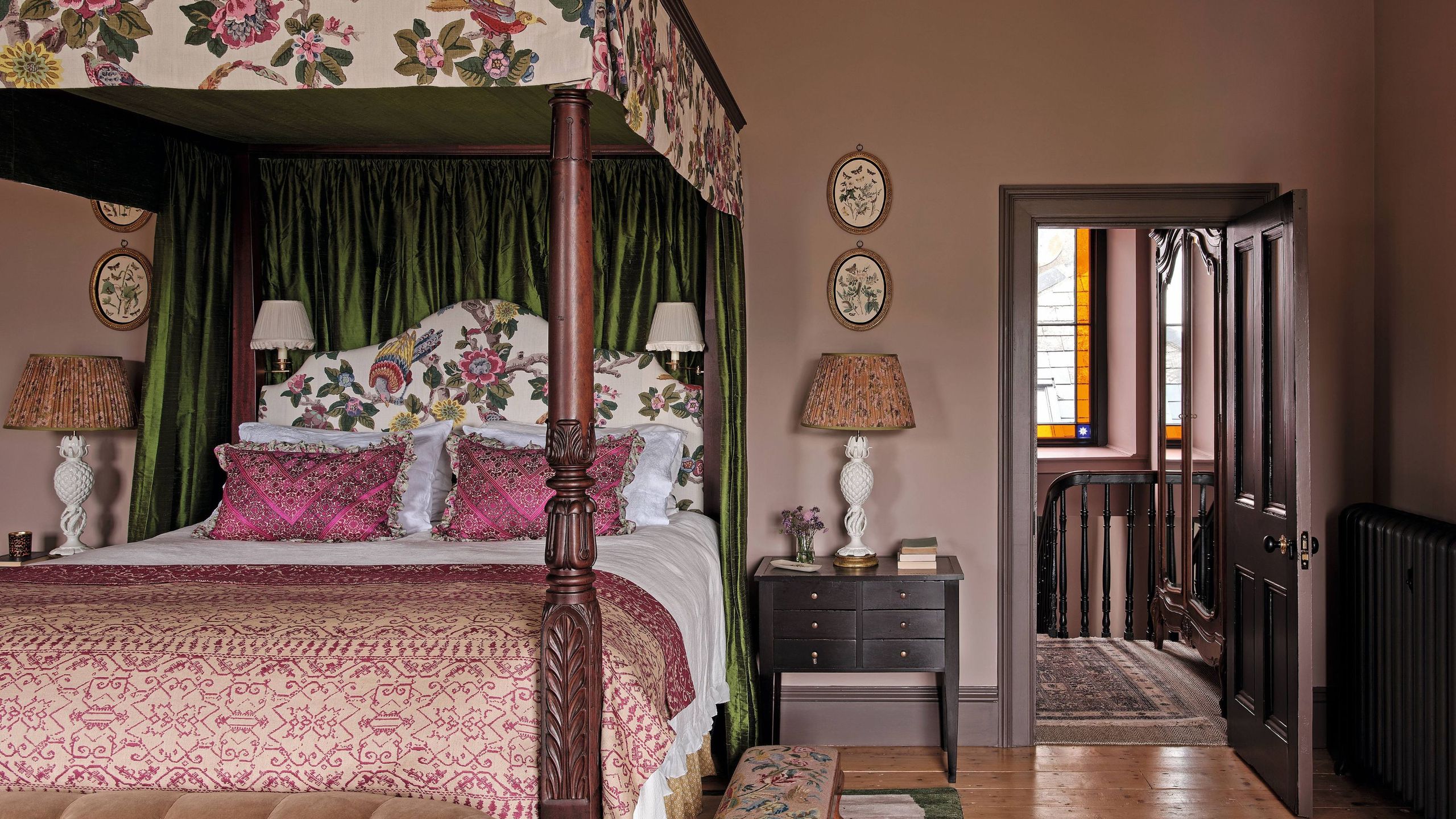 a moody mauve traditional english bedroom with floral canopy four poster antique bed and layered patterned bed linens